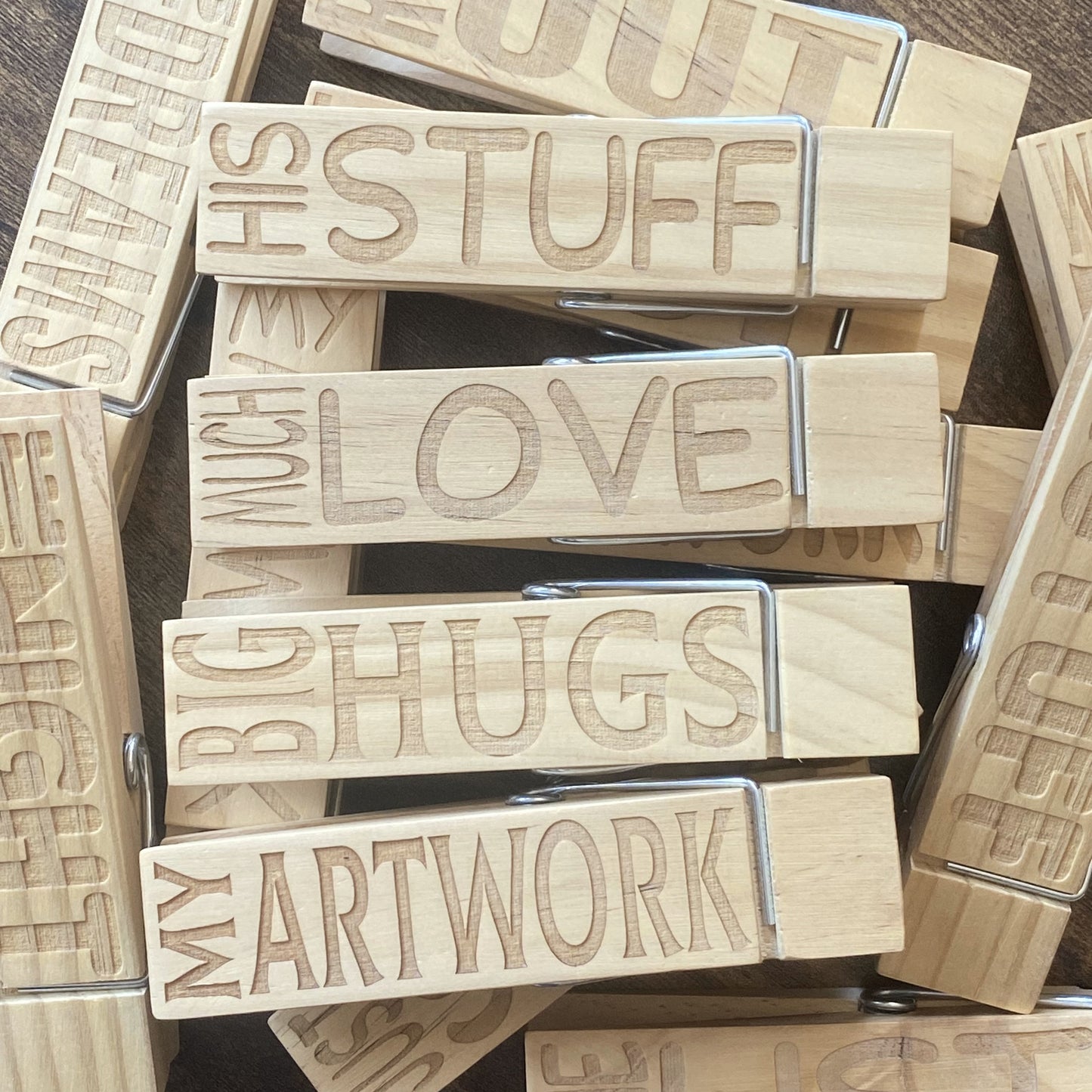 A top-down view of multiple Jumbo Pegs stacked, showcasing the smooth natural wood and engraved designs.