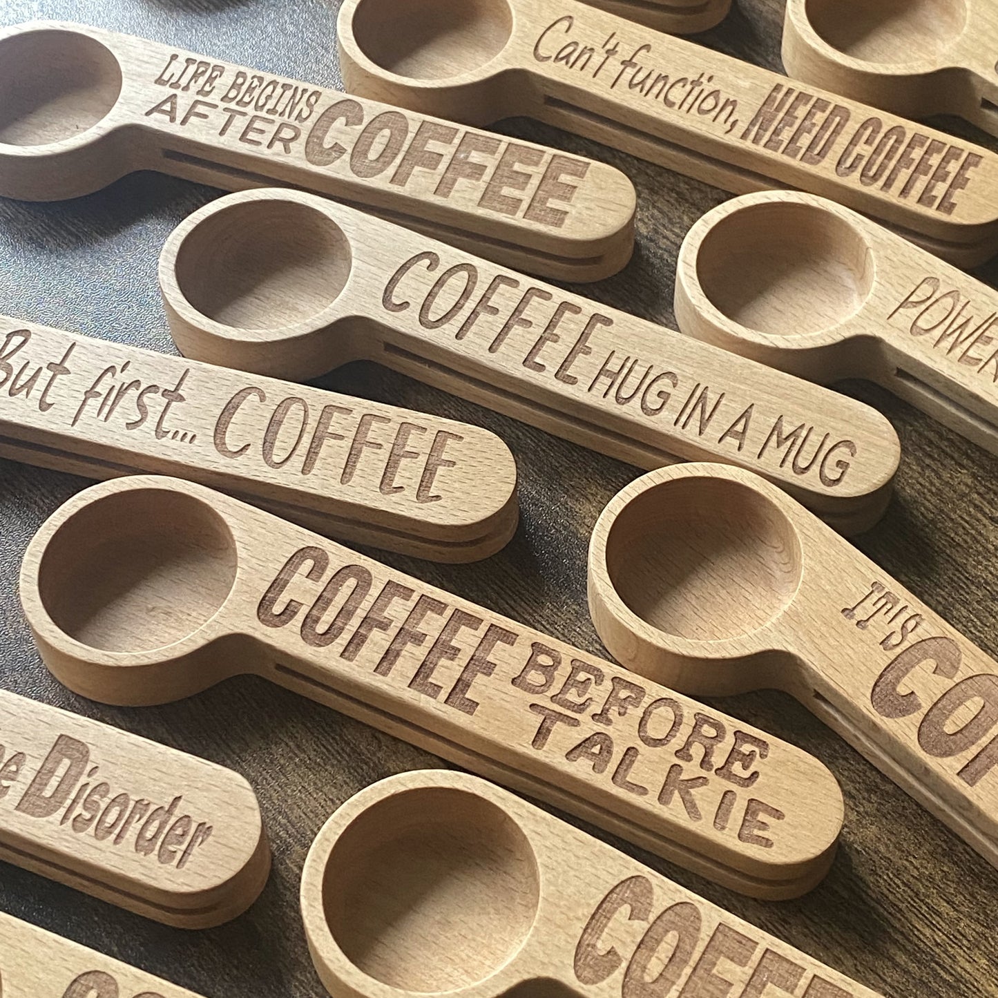 A collection of beautifully engraved wooden coffee spoons, showcasing different designs and quotes.