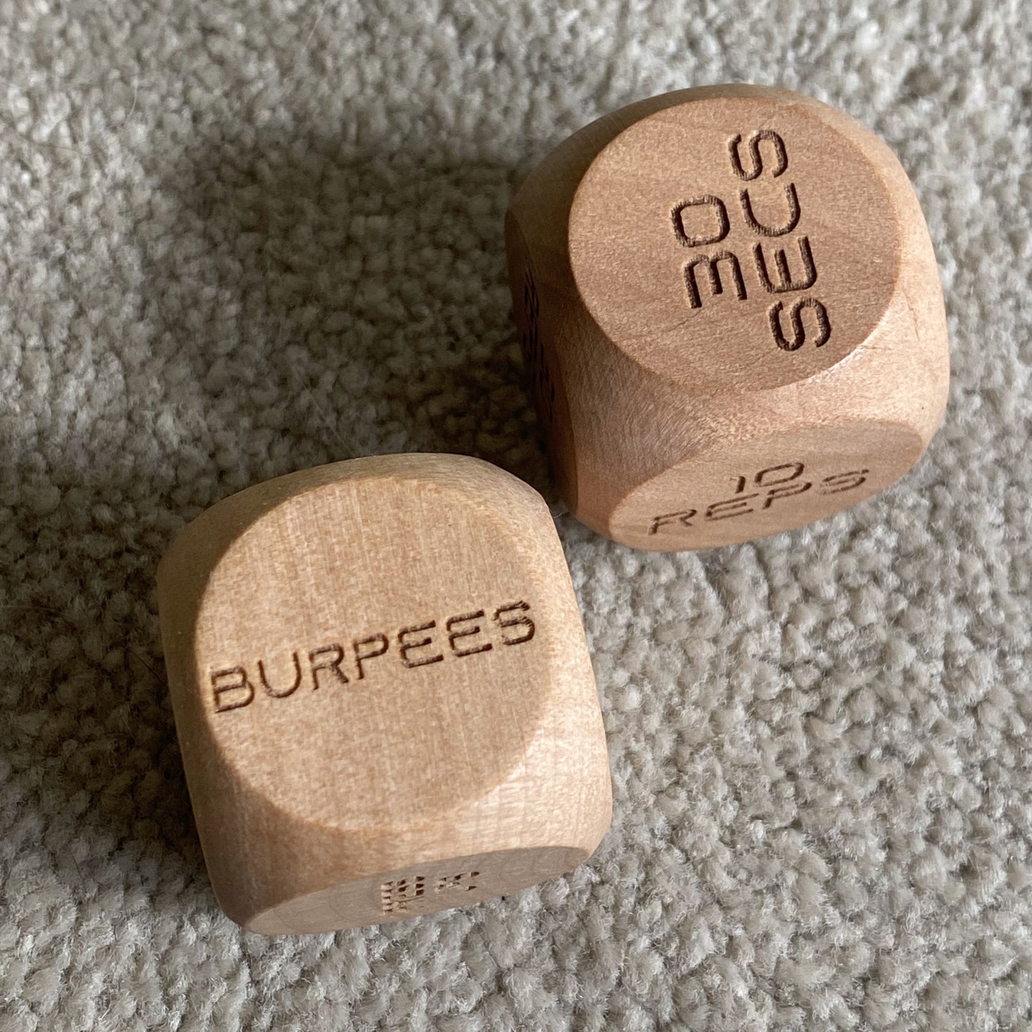 Adult Exercise Decision Dice pair at home, top-down view displaying detailed engraved workout prompts