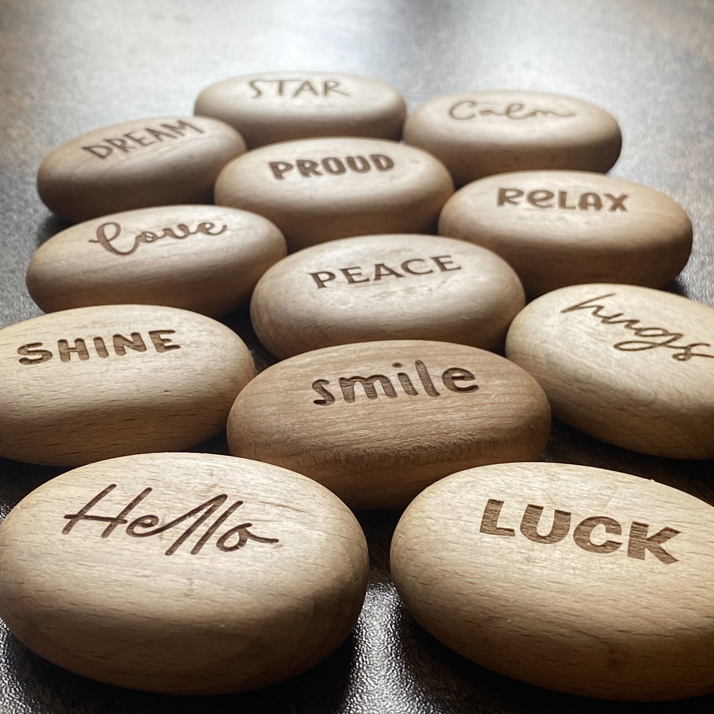 Angled display of Affirmation Edition wooden pocket pebbles – engraved with uplifting words and presented as a calming gift set