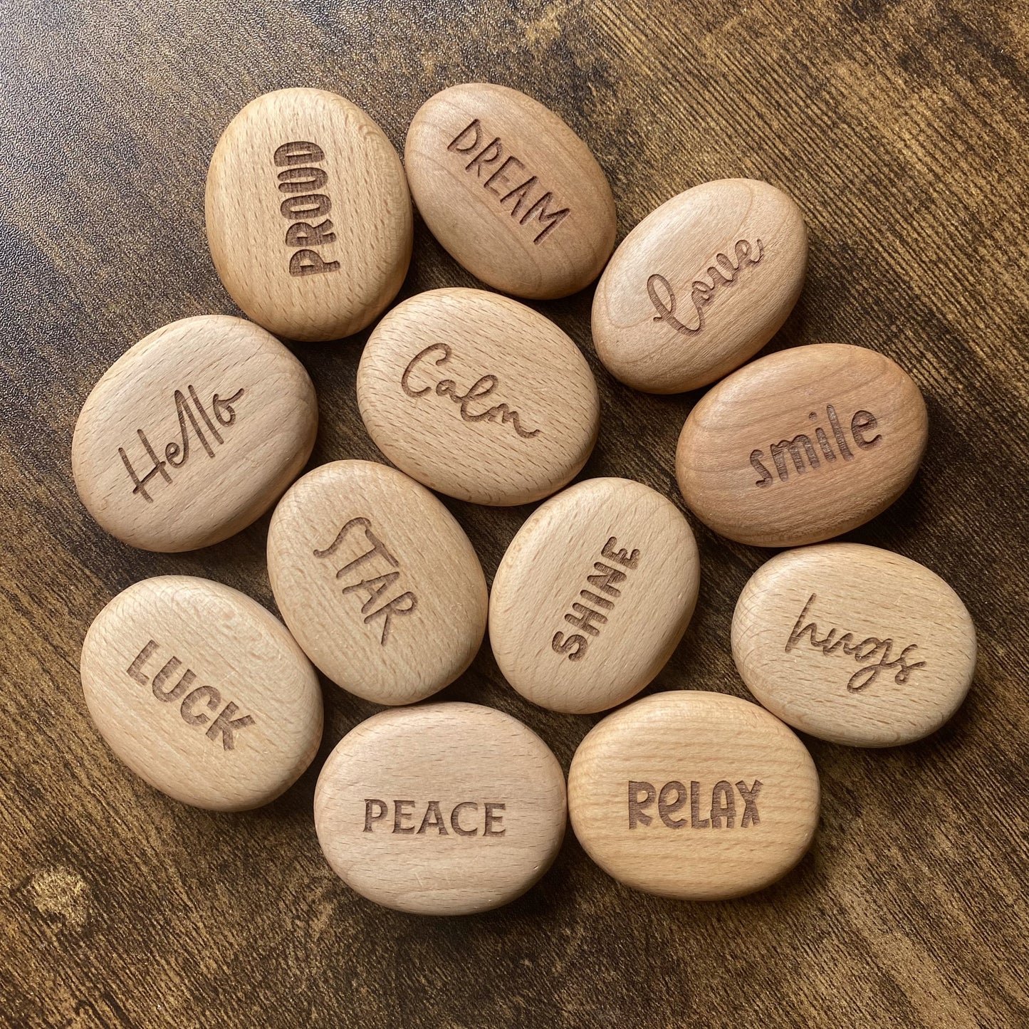 Top-down view of Affirmation Edition wooden pebbles – engraved with comforting words and arranged as a full collection