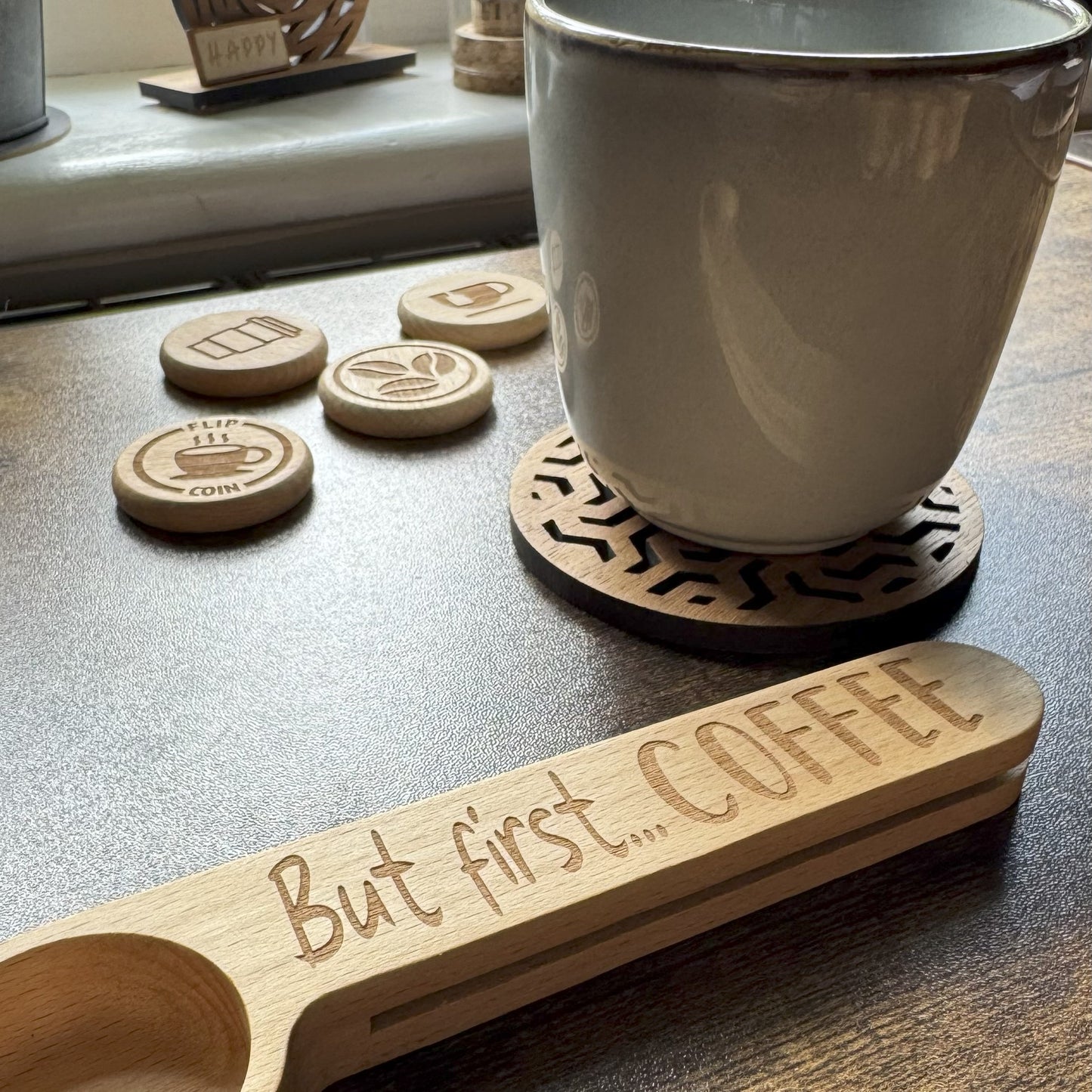 Engraved coffee spoon with mug of coffee, with coins flipped in the background, styled for a playful and cosy beverage moment