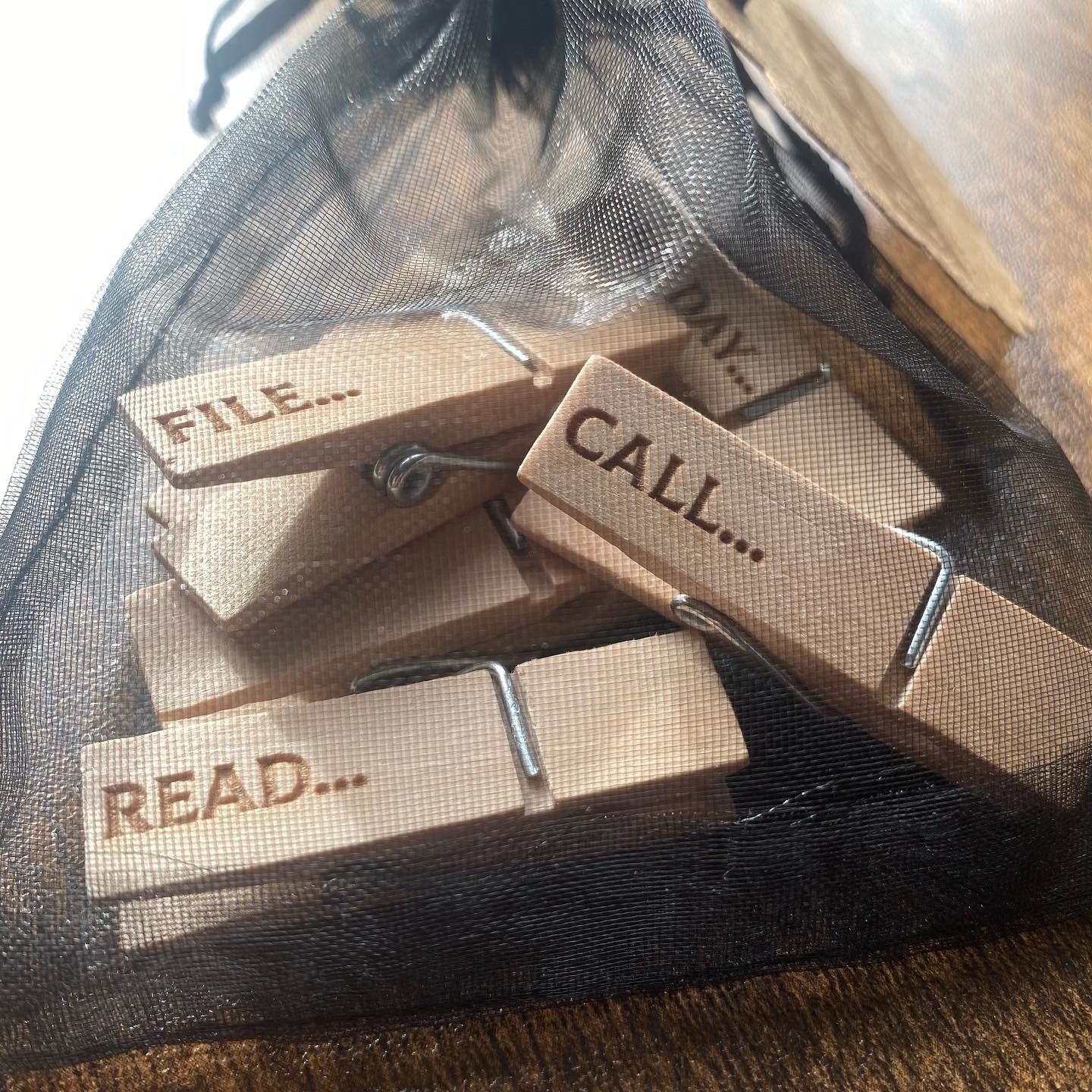 Soft organza bag containing six natural wood mini desk organisation pegs with visible engraved details, neatly stored for easy organisation.
