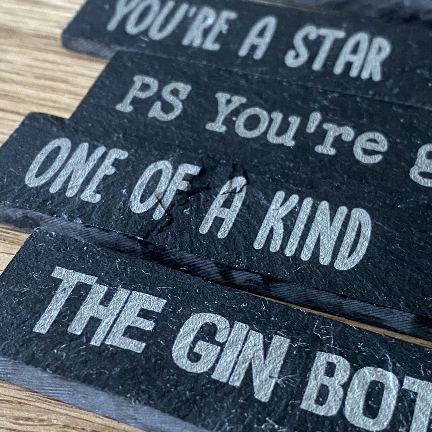 Side-angled detail of engraved slate plant markers with mixed designs