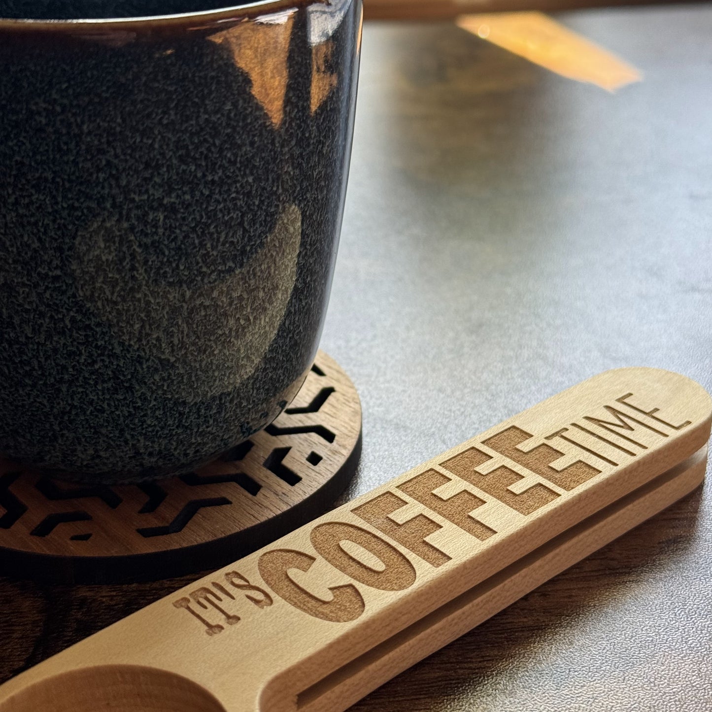 It’s Coffee Time engraved spoon resting in front of a mug with walnut cut coaster