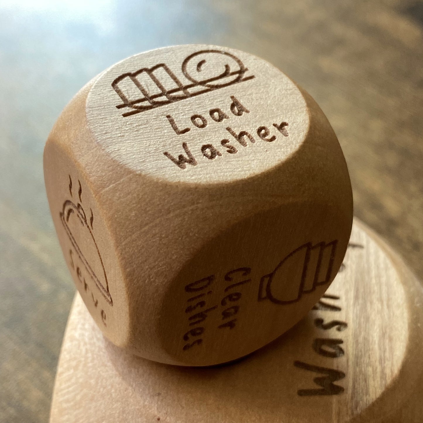 Close-up of pocket size Junior Chores Decision Dice with clear engraved illustrations for young children