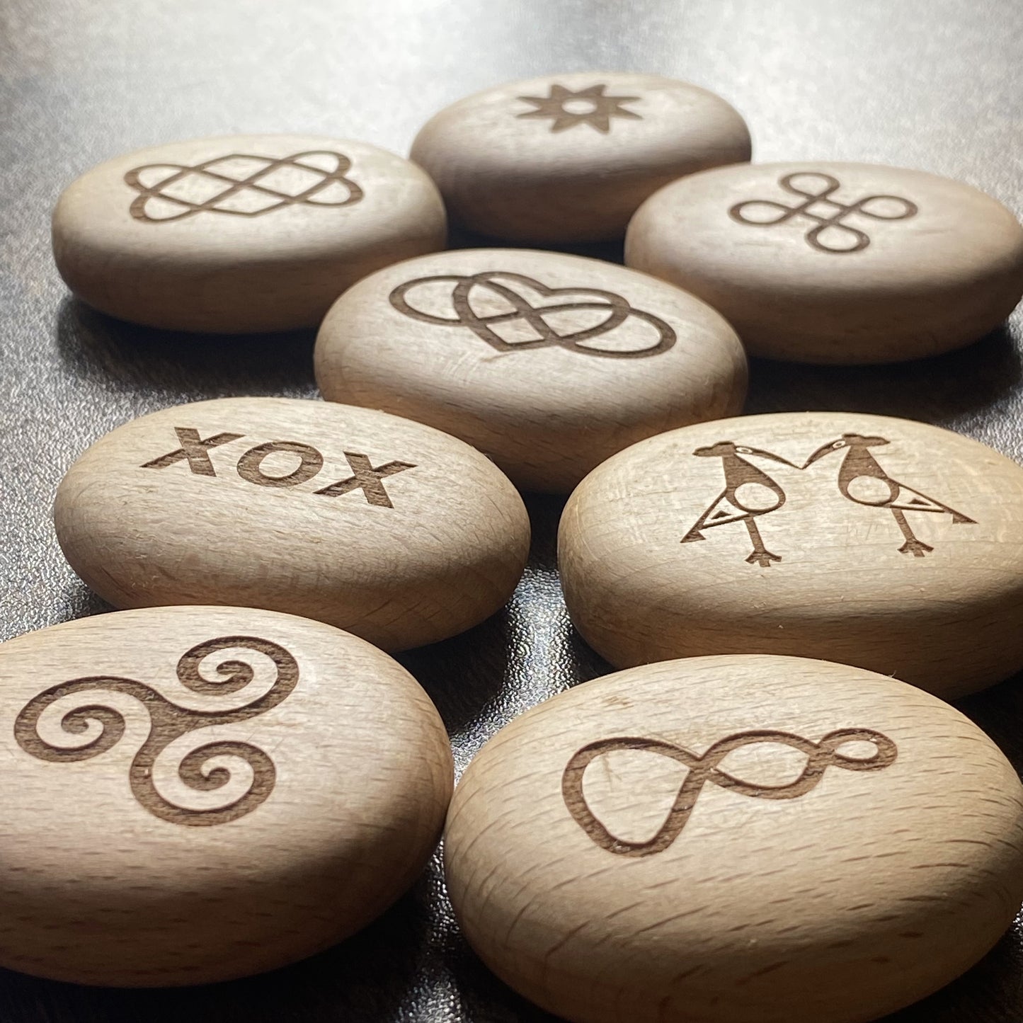 Angled display of Love Edition wooden pocket pebbles – engraved with symbols of connection and affection