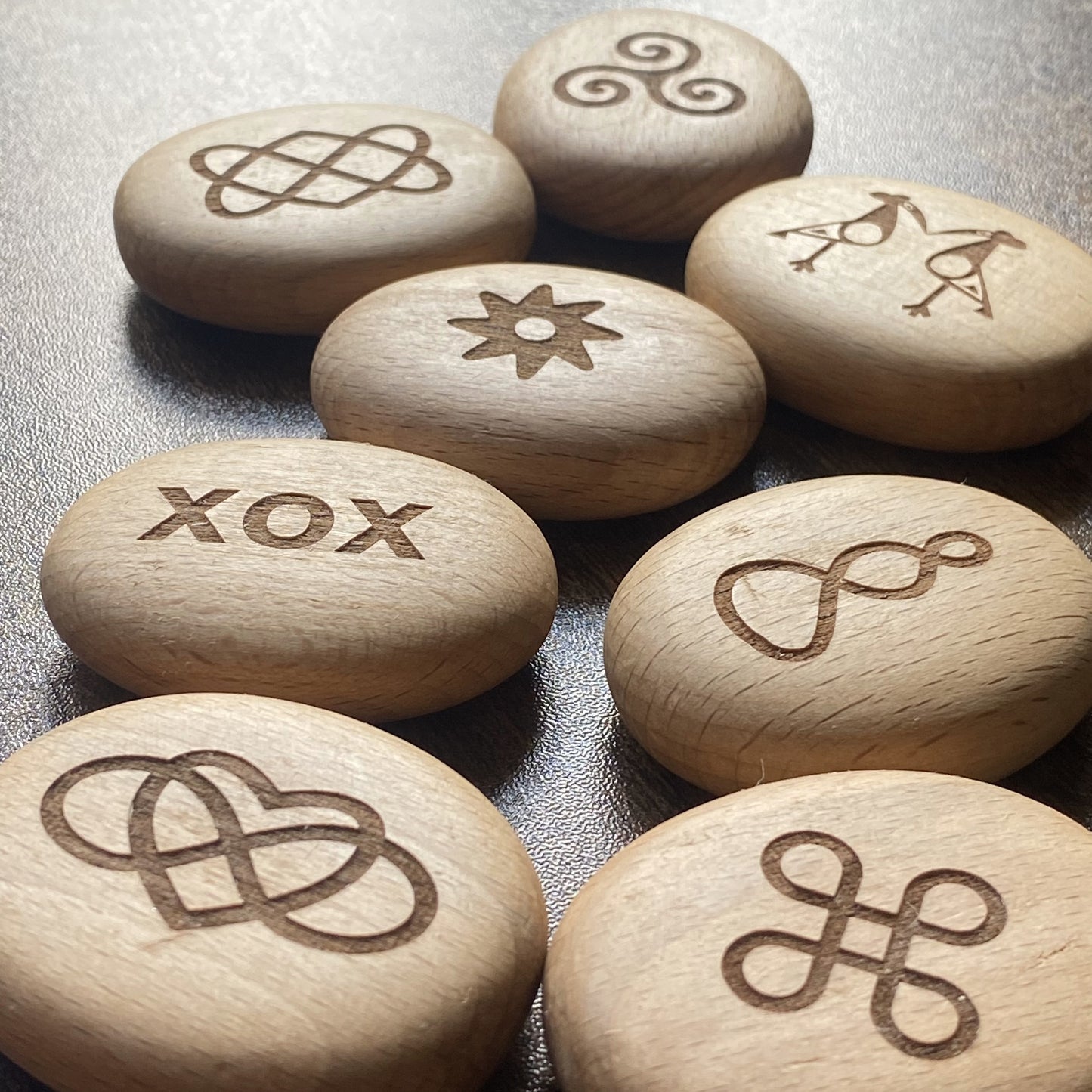 Engraved wooden Love Edition pocket pebbles shown at an angle – each with a unique symbol of love