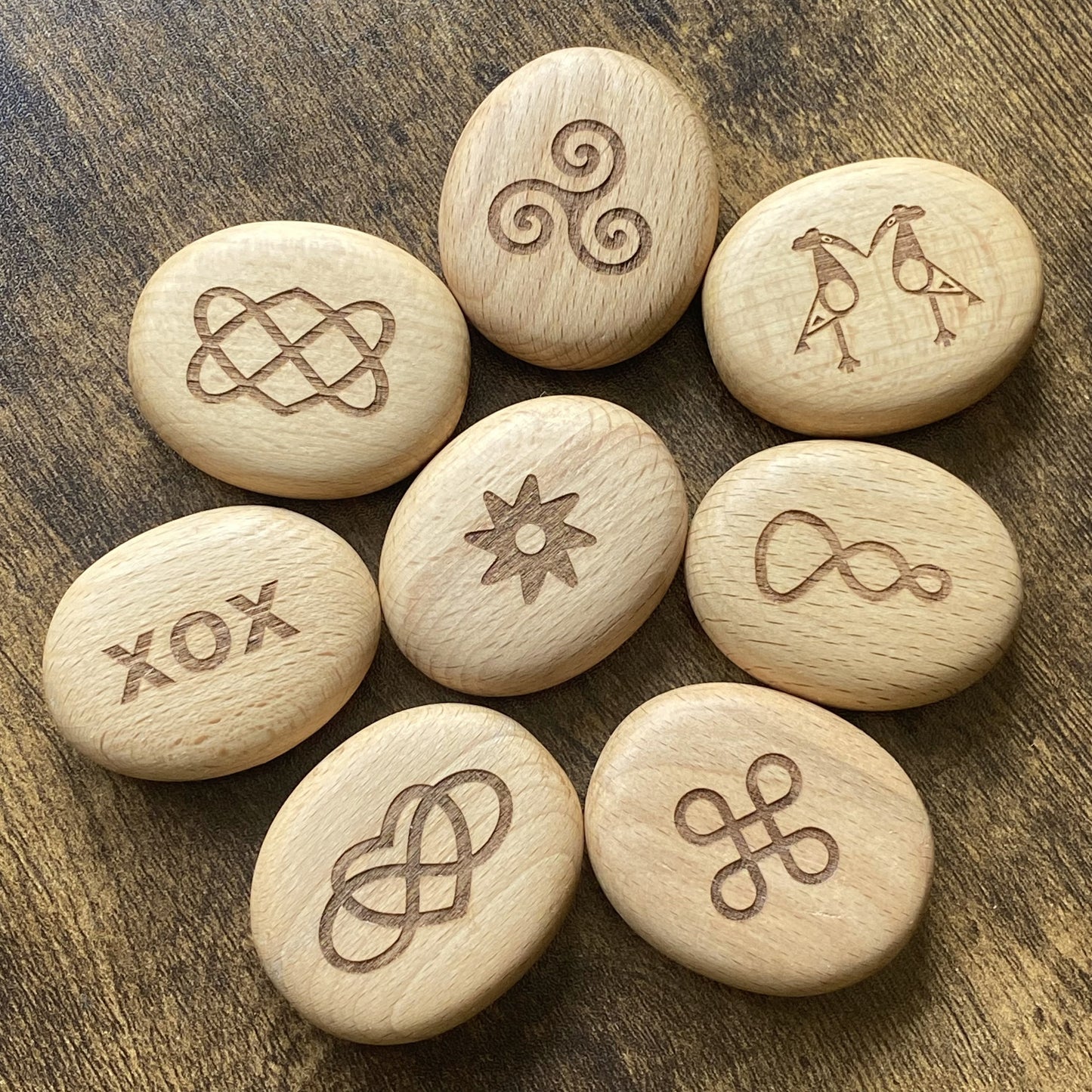 Top-down view of Love Edition wooden pocket pebbles – symbolic designs arranged in a full set display