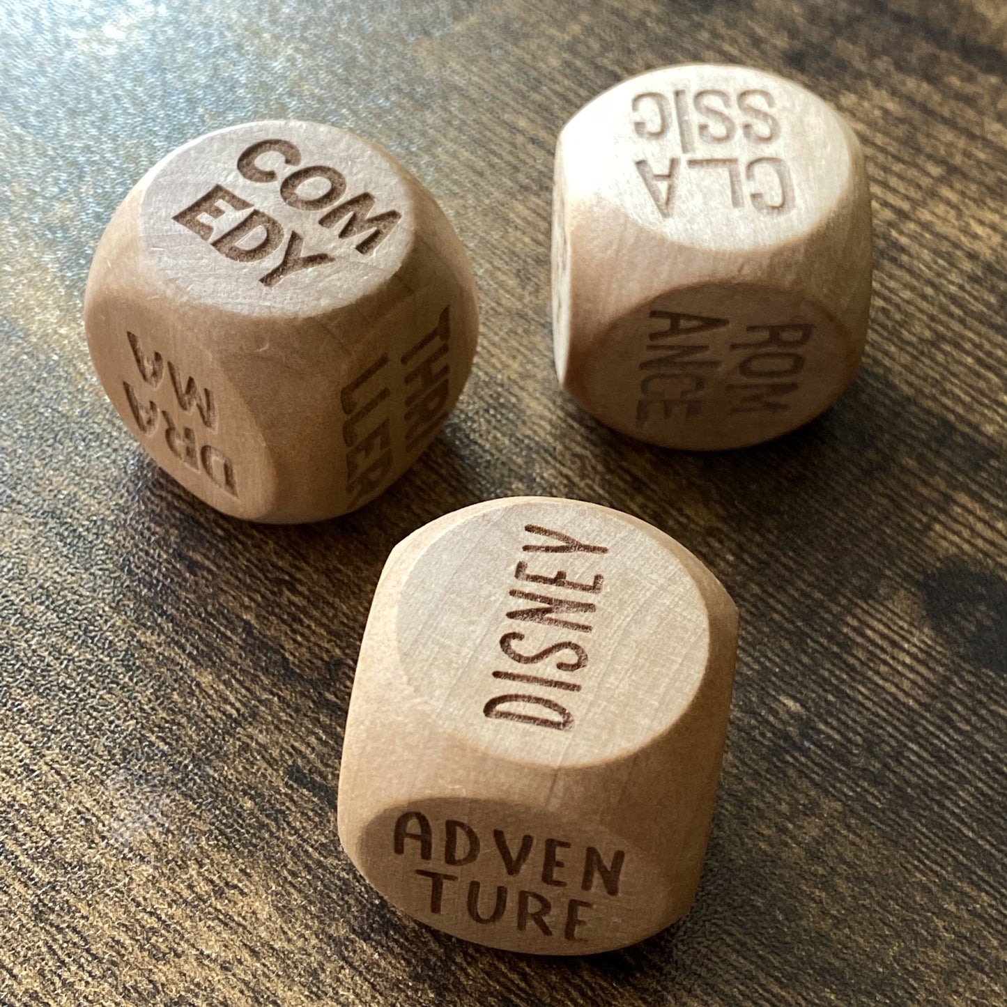Rolled Movie Night Decision Dice showing engraved genre names and the smooth wooden texture of the dice