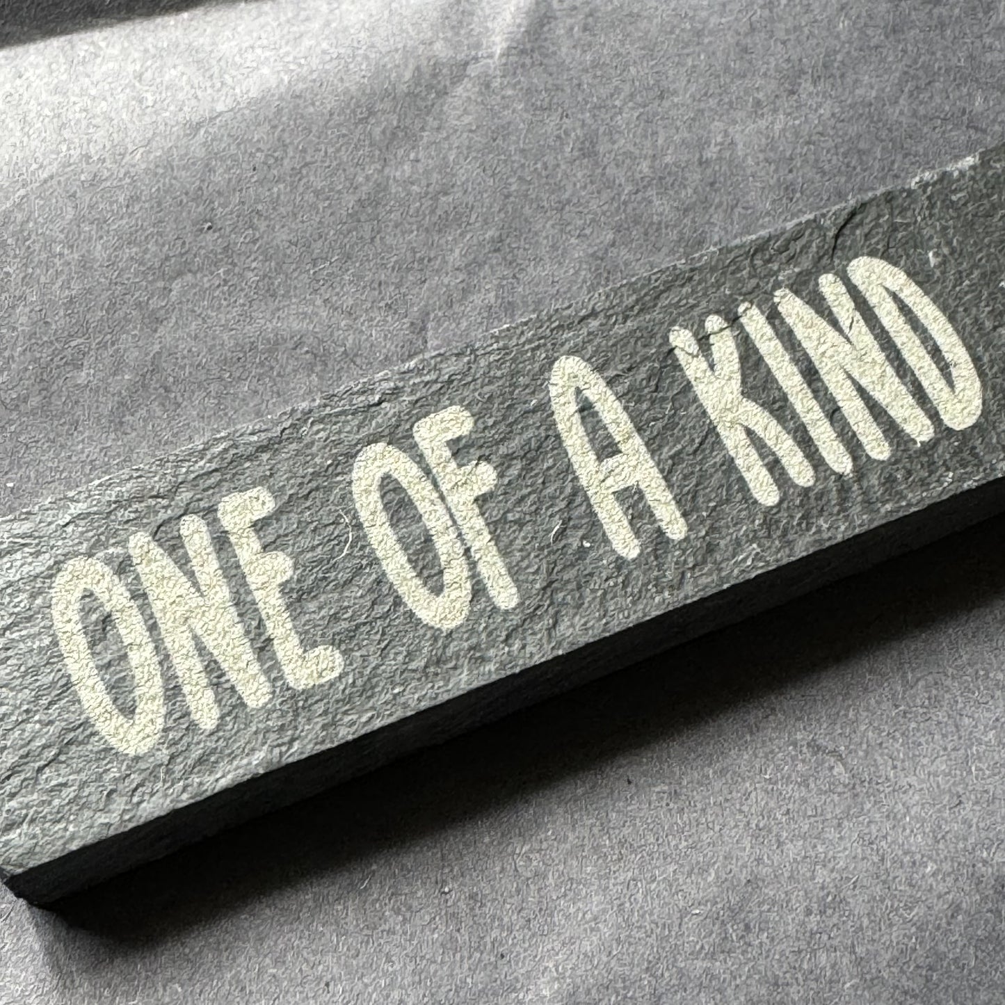Close-up of ‘One of a Kind’ engraved slate marker resting on tissue paper, ready for gifting