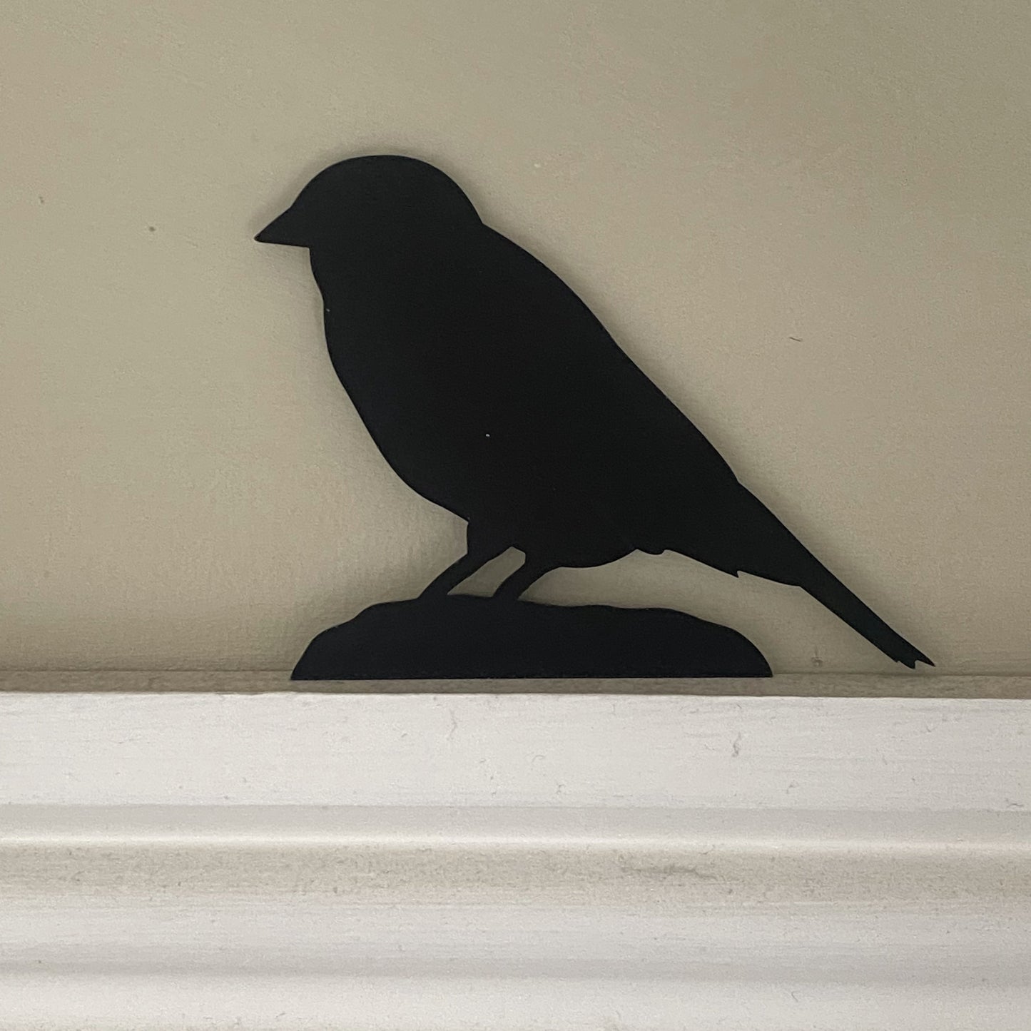 Studio-designed black sparrow silhouette sculpture perched above a door frame, adding a subtle nature-inspired detail to interior decor
