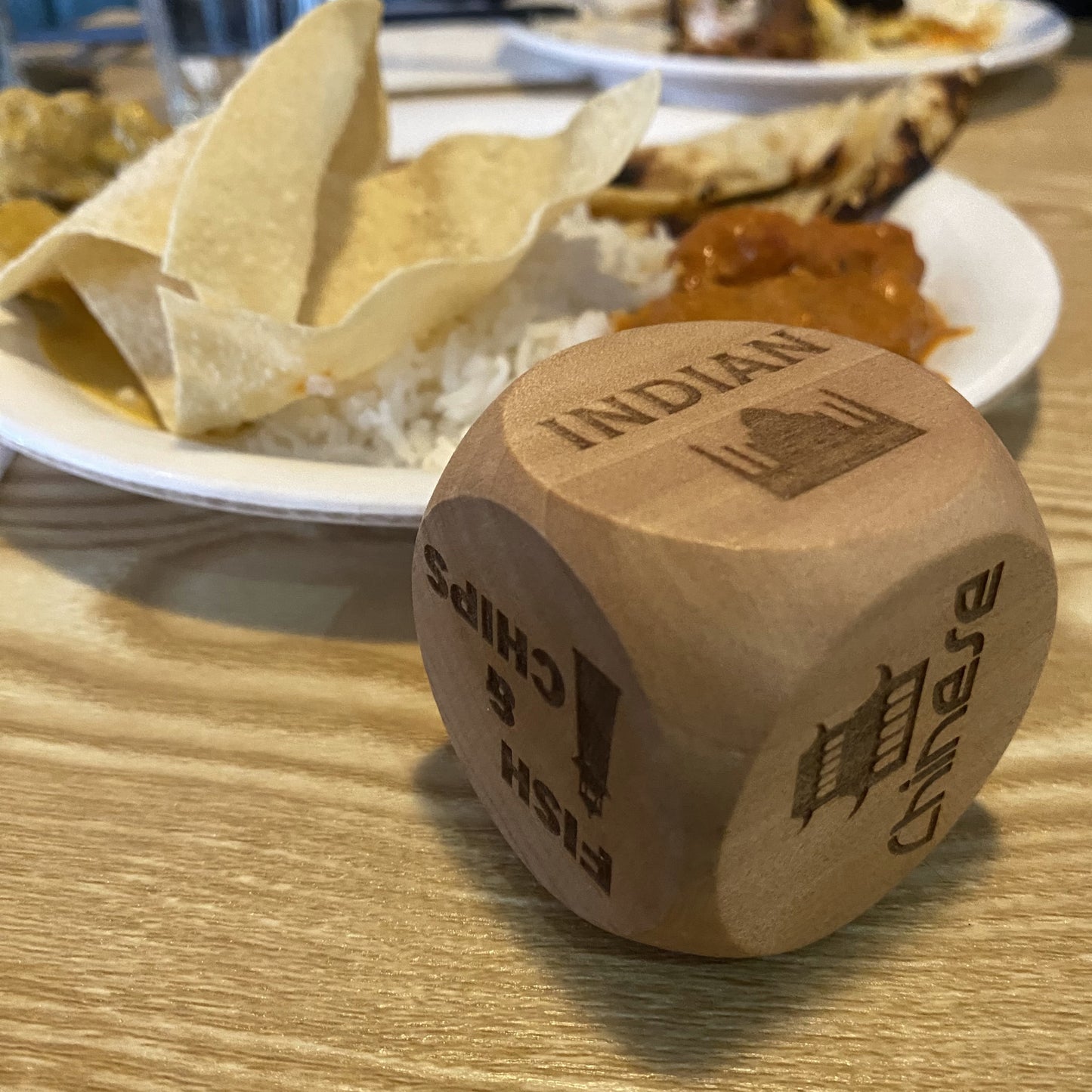 Takeout Decision Dice showing 'Indian' next to a plated Indian meals on a dining table