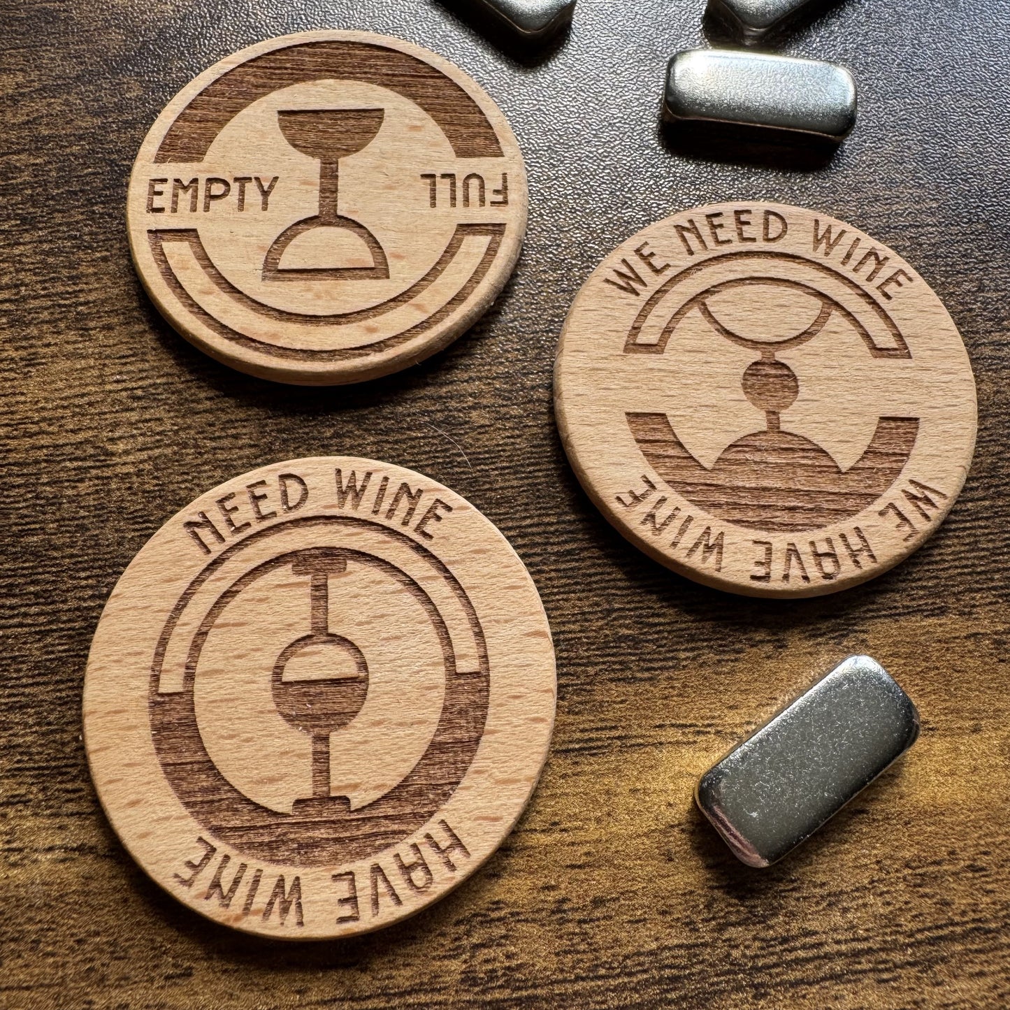 Close-up top-down view of three 'The Wine Dial' spinning status dial designs displayed together with magnetic striker buttons