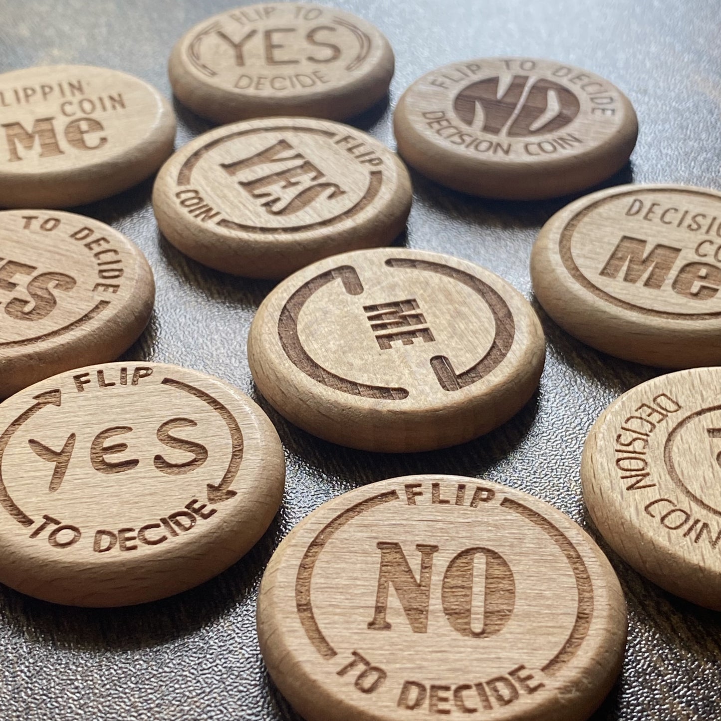 A tabletop shot displaying all the unique designs of the Ultimate Decision Maker Coin, showcasing the variety and engraved details