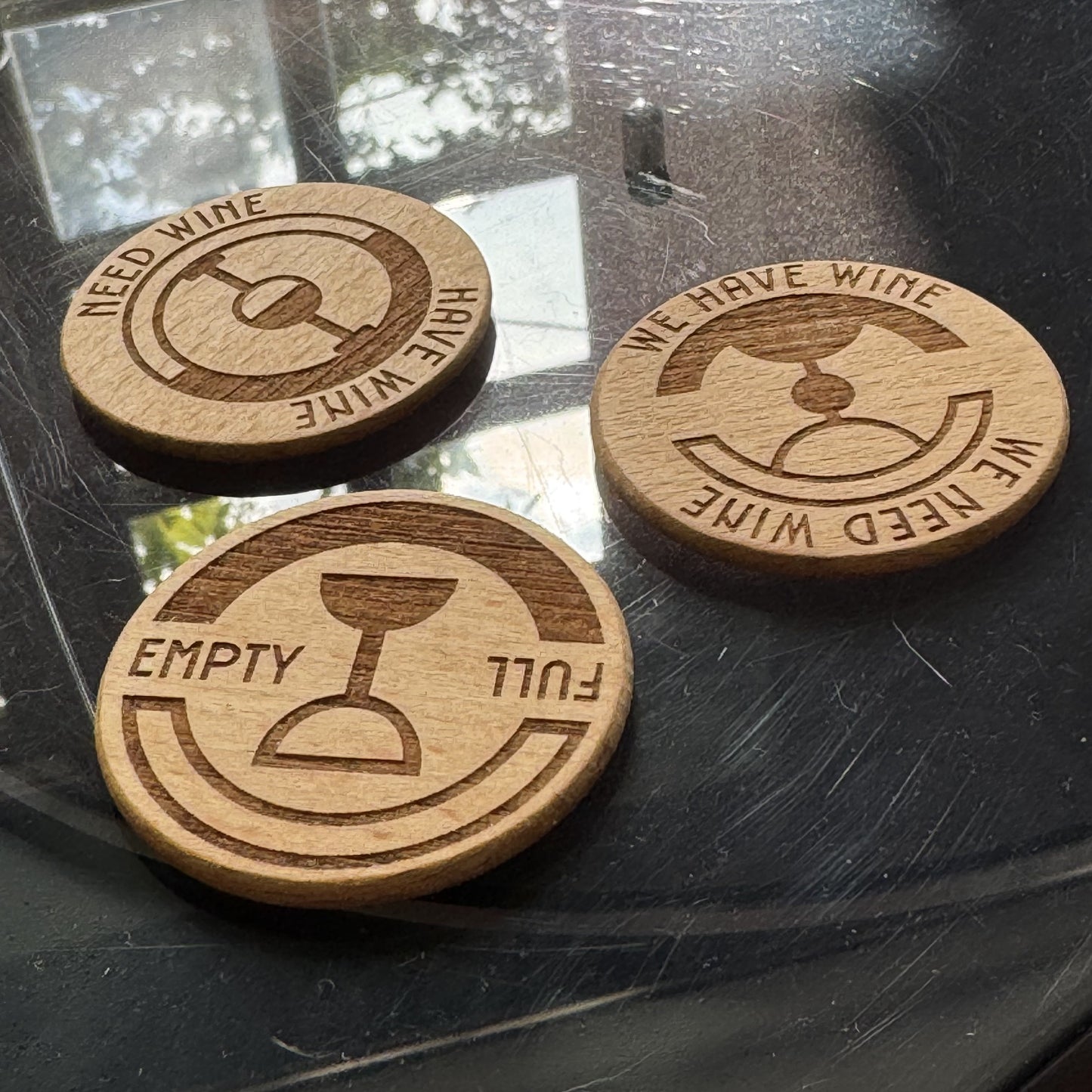 Angled lifestyle shot of three engraved Wine Status Dials on reflective background