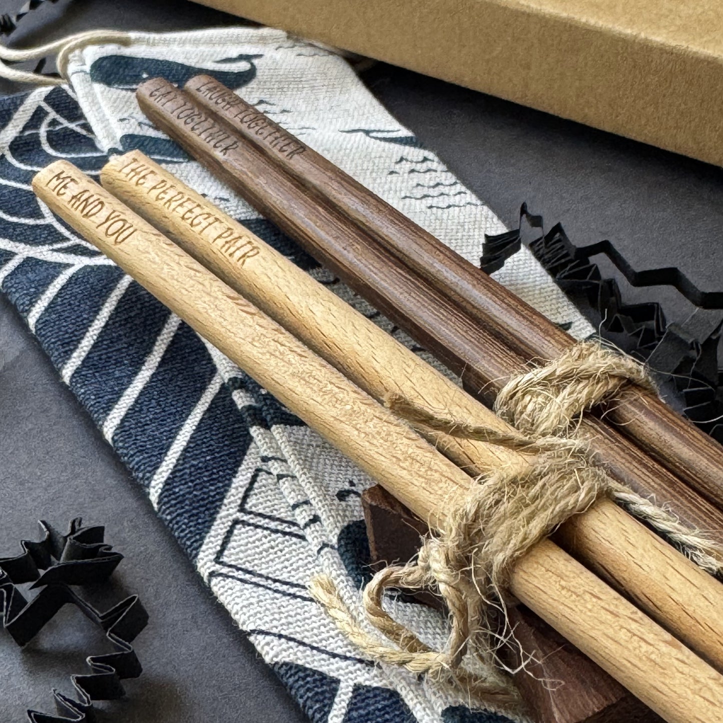 Pair of engraved wooden chopsticks with personal messages, one light and one dark wood, elegantly presented and ready for gifting.