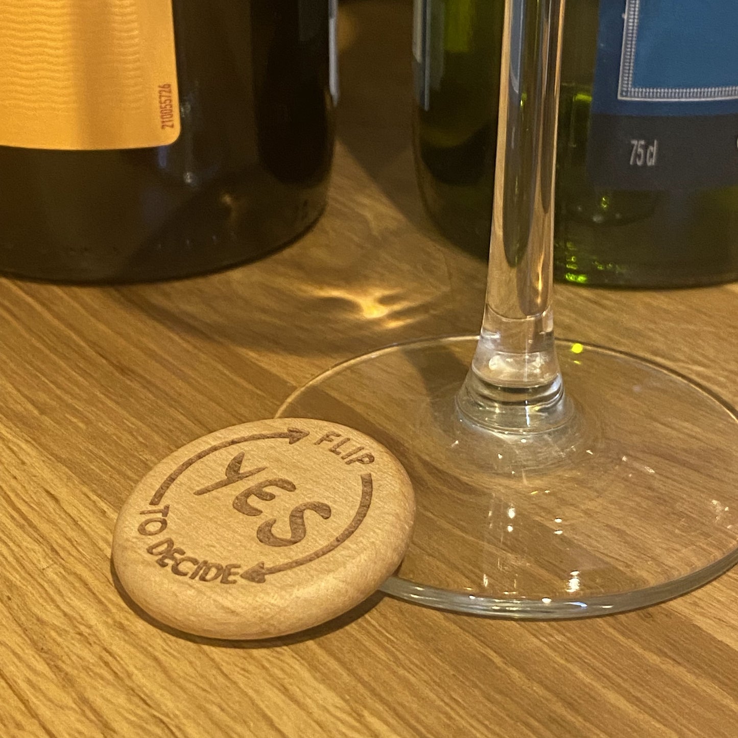 Yes No Ultimate Flip to Decide Coin placed beside wine bottle and glass stem – playful decision maker