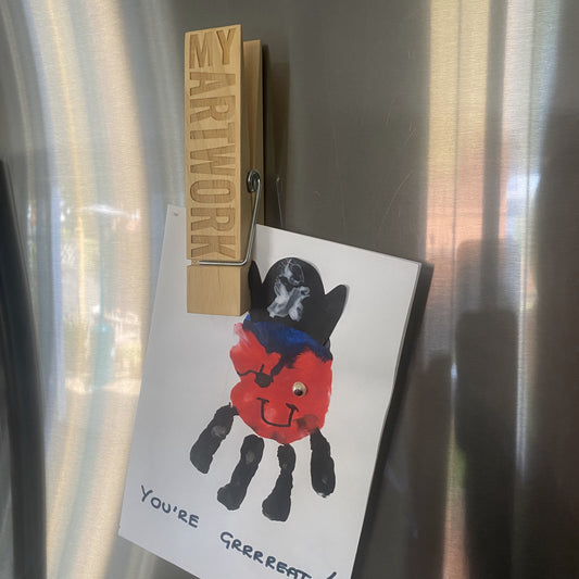 A child’s drawing held up on a fridge with a Jumbo Peg, keeping the artwork visible and secure.