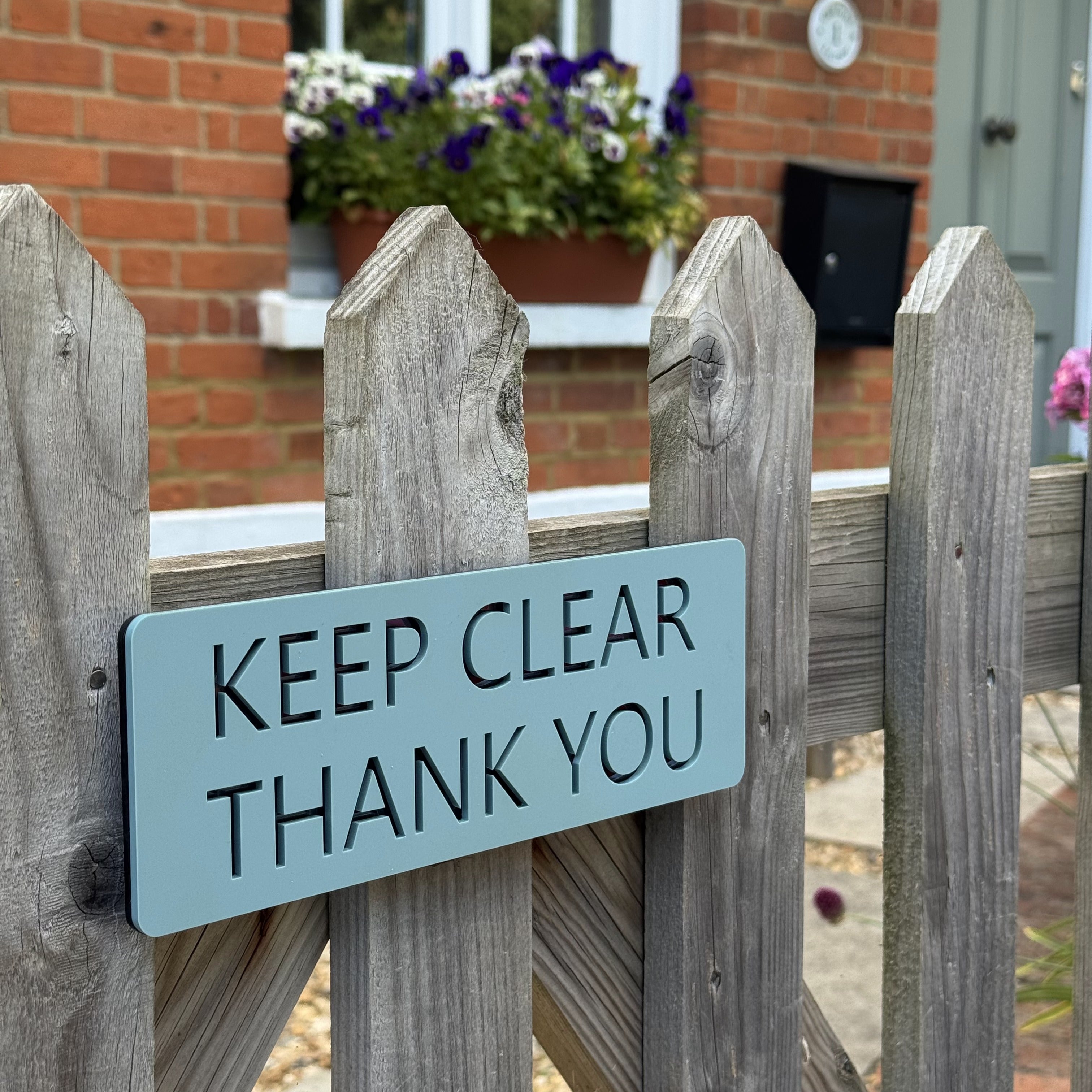 Bespoke acrylic gate sign in duck egg blue with mirrored slate layer, installed on a wooden garden gate outside a Hampshire cottage to prevent being blocked by parking.