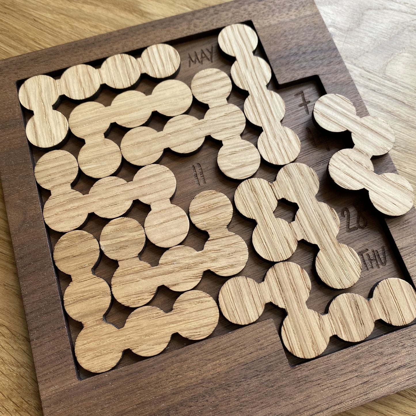 Top-down view of the Daily Perpetual Calendar Puzzle, showcasing intricate grain details and engraved design.