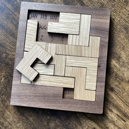 Angled top-down view of oak wooden calendar puzzle with square pieces and engraved detailing