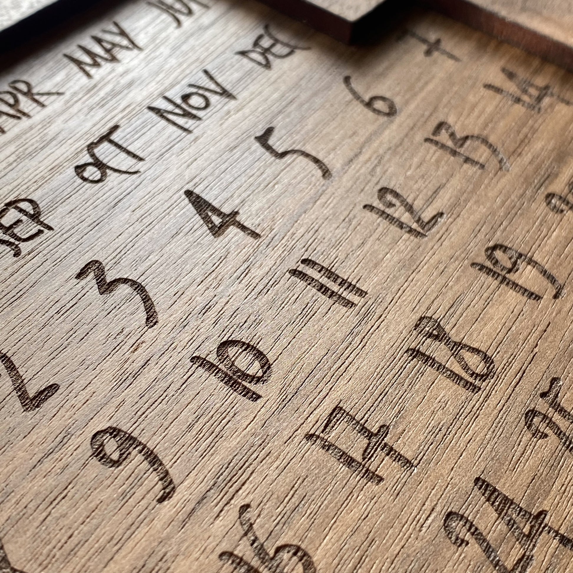 Close-up of engraved wooden calendar puzzle showing fine detail and date layout