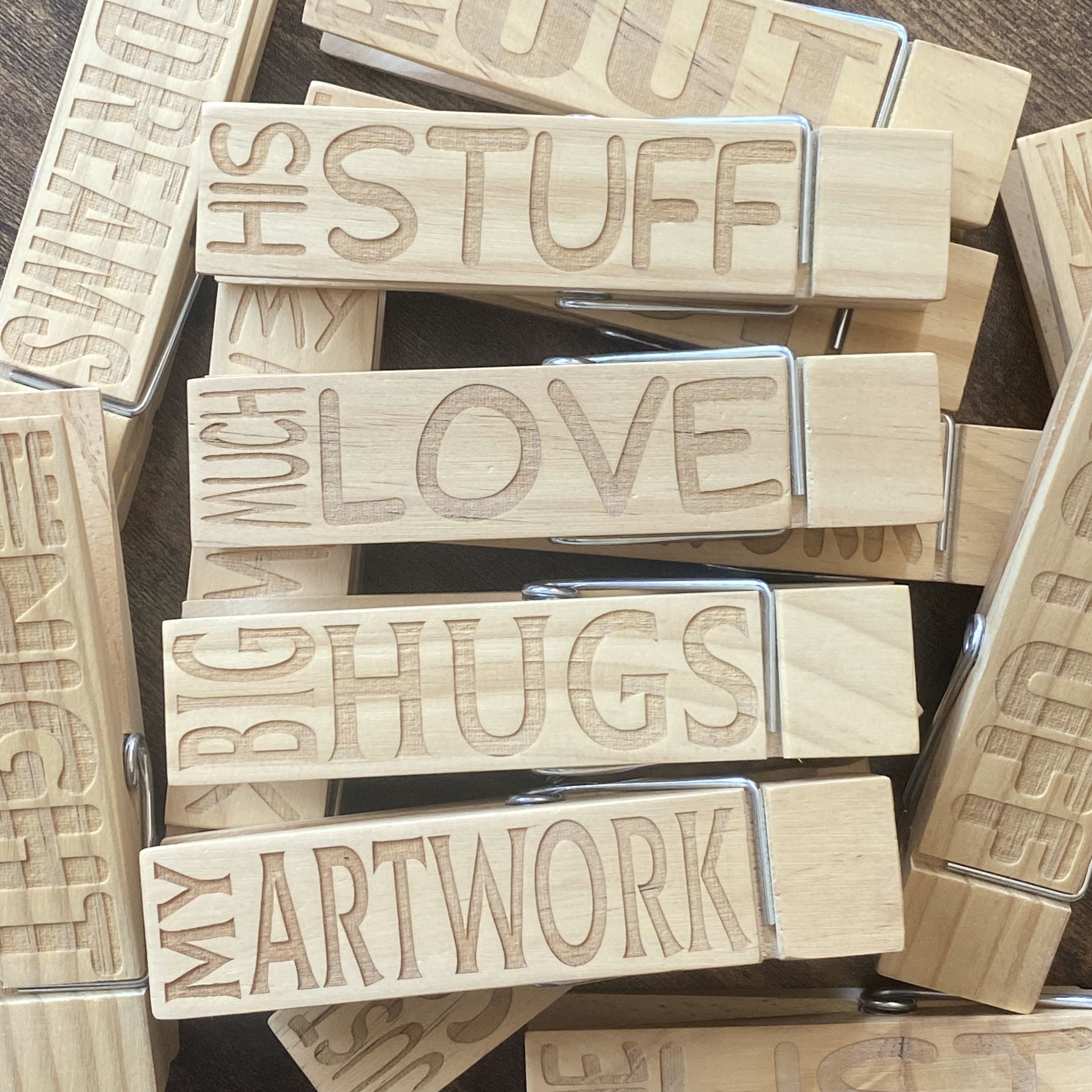 A top-down view of multiple Jumbo Pegs stacked, showcasing the smooth natural wood and engraved designs.