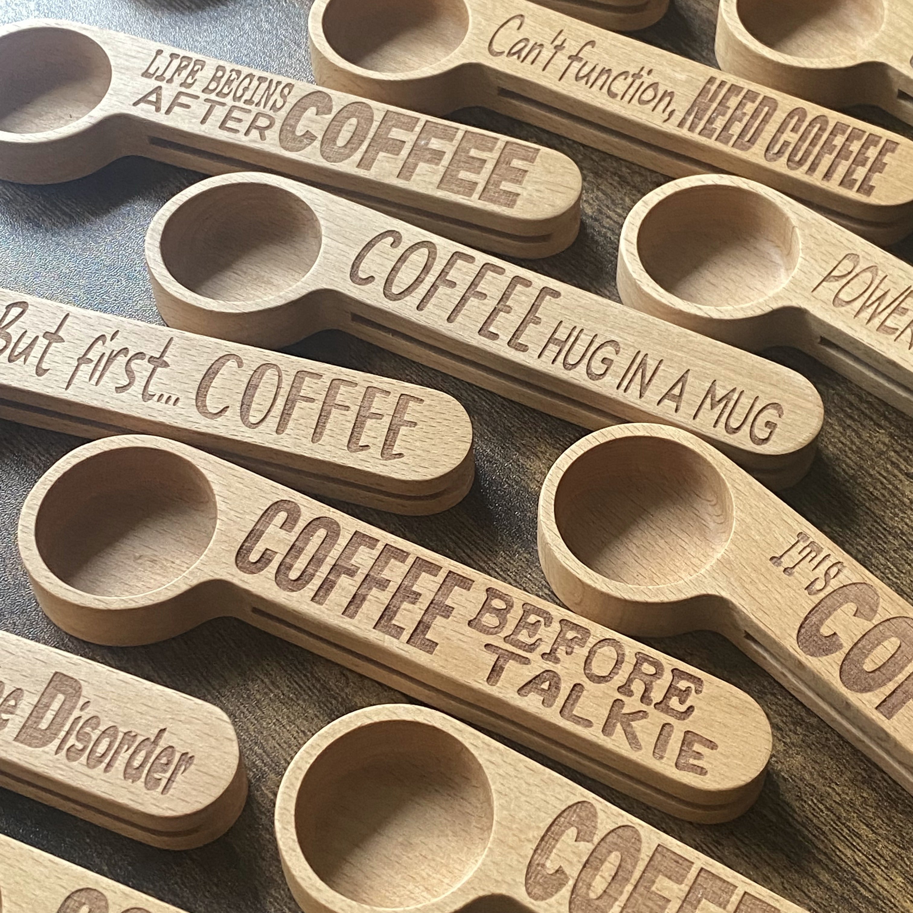 A collection of beautifully engraved wooden coffee spoons, showcasing different designs and quotes.