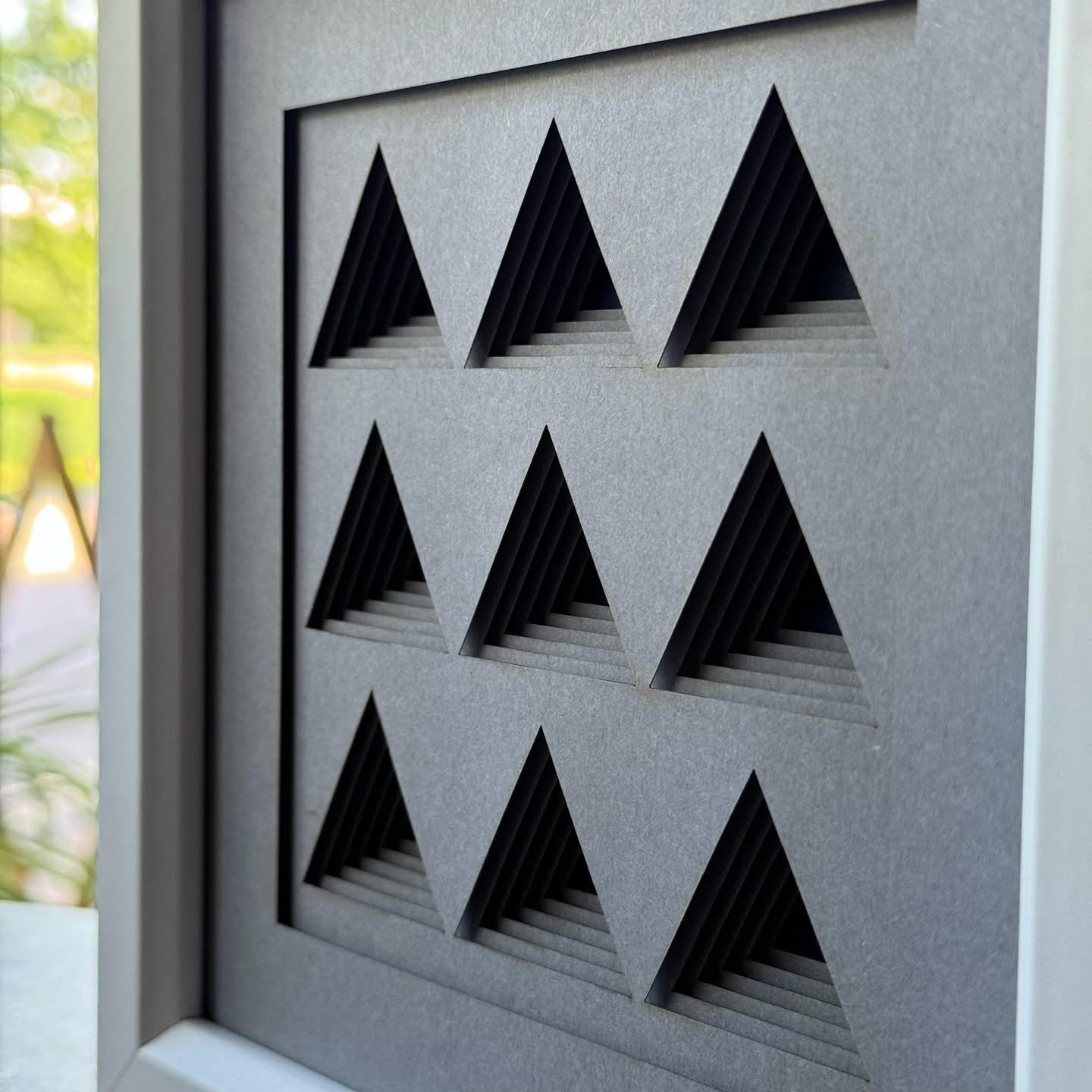 Angled view of layered artwork featuring bold geometric shapes and precise cut lines
