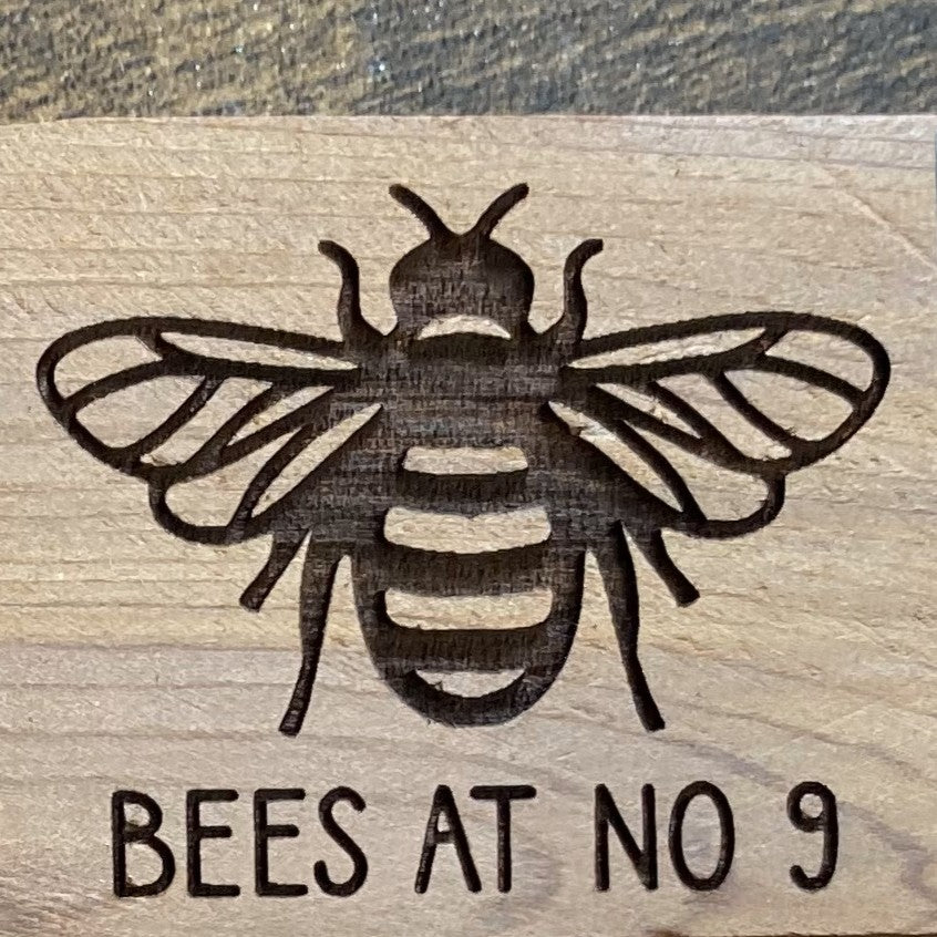 Bee logo precisely laser engraved on wooden surface, showcasing detailed craftsmanship