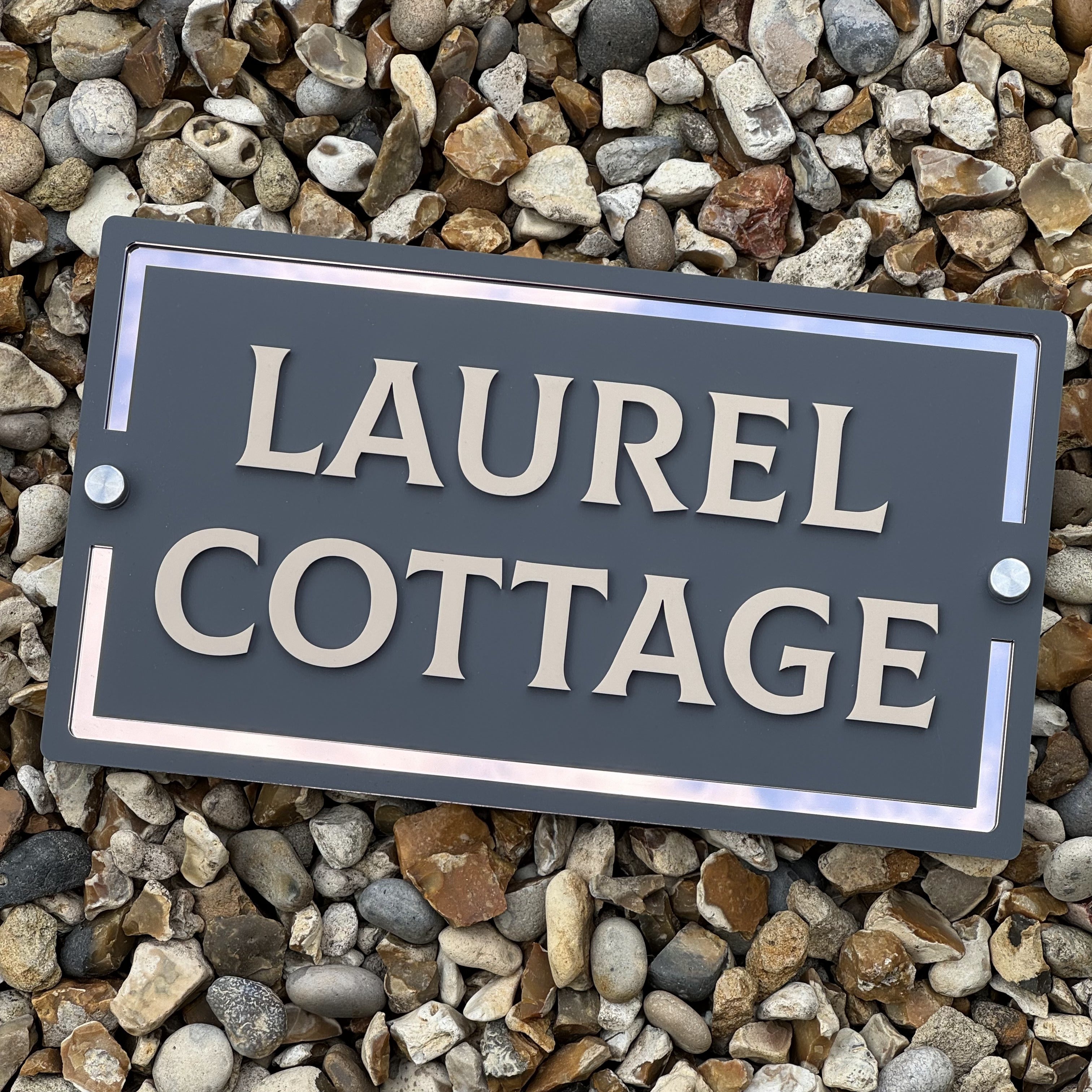 Bespoke acrylic house sign by In the Oaks, displayed on a bed of smooth pebbles