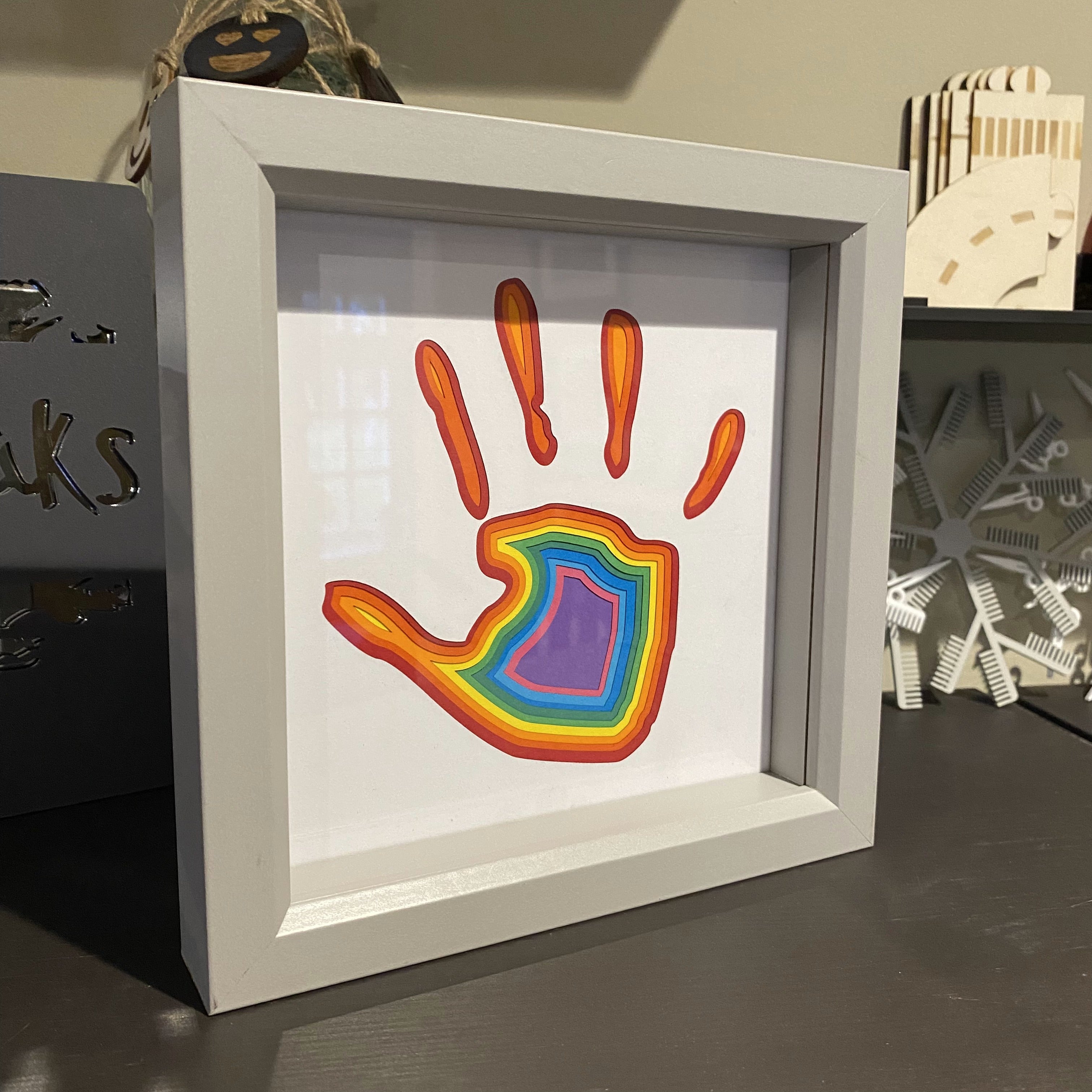 Framed layered artwork of child’s handprint in rainbow colours – personalised keepsake made from cut paper