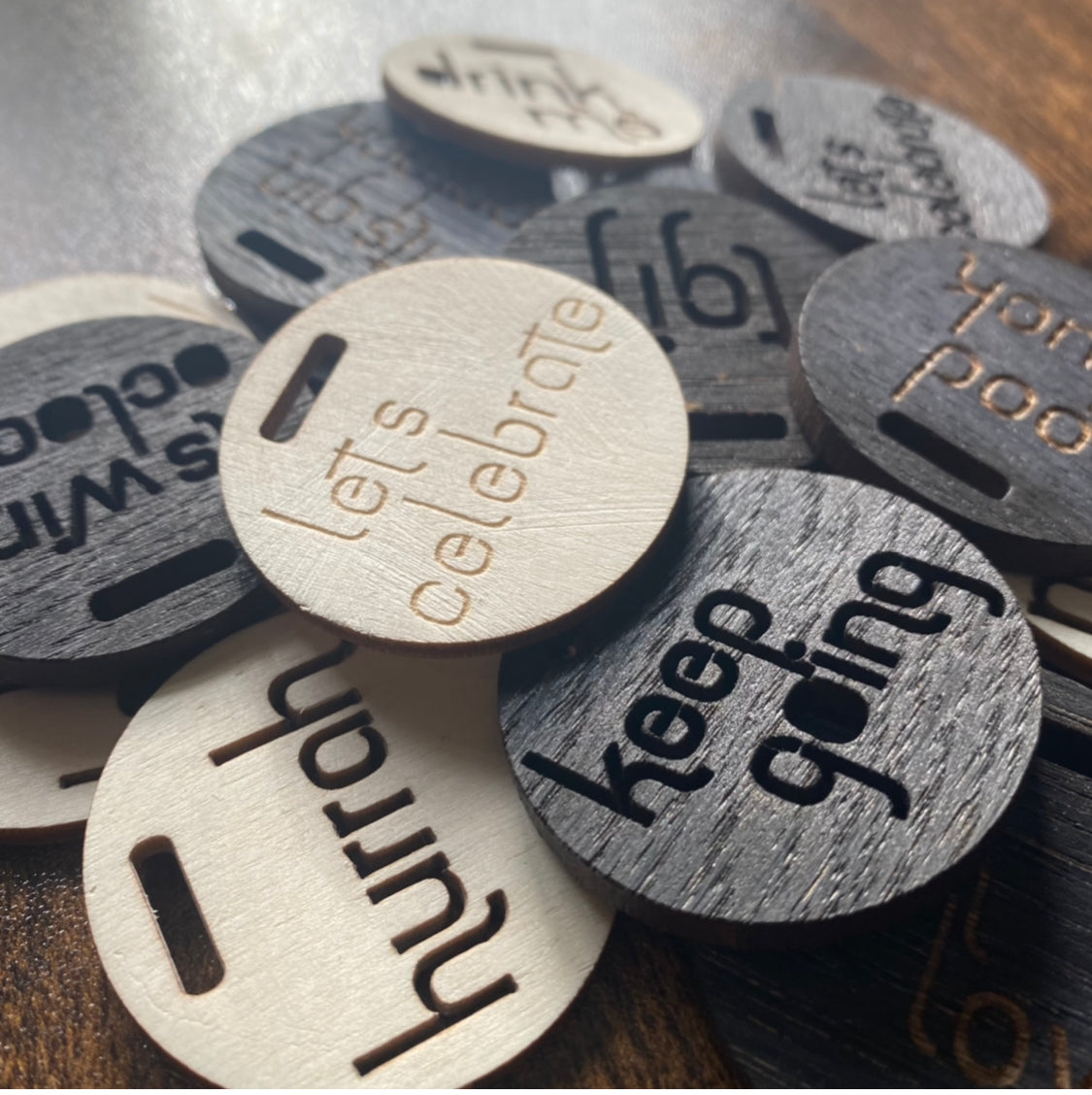 Scattered pile of wooden engraved bottle charms photographed at an angle – ideal for gifting and celebrations