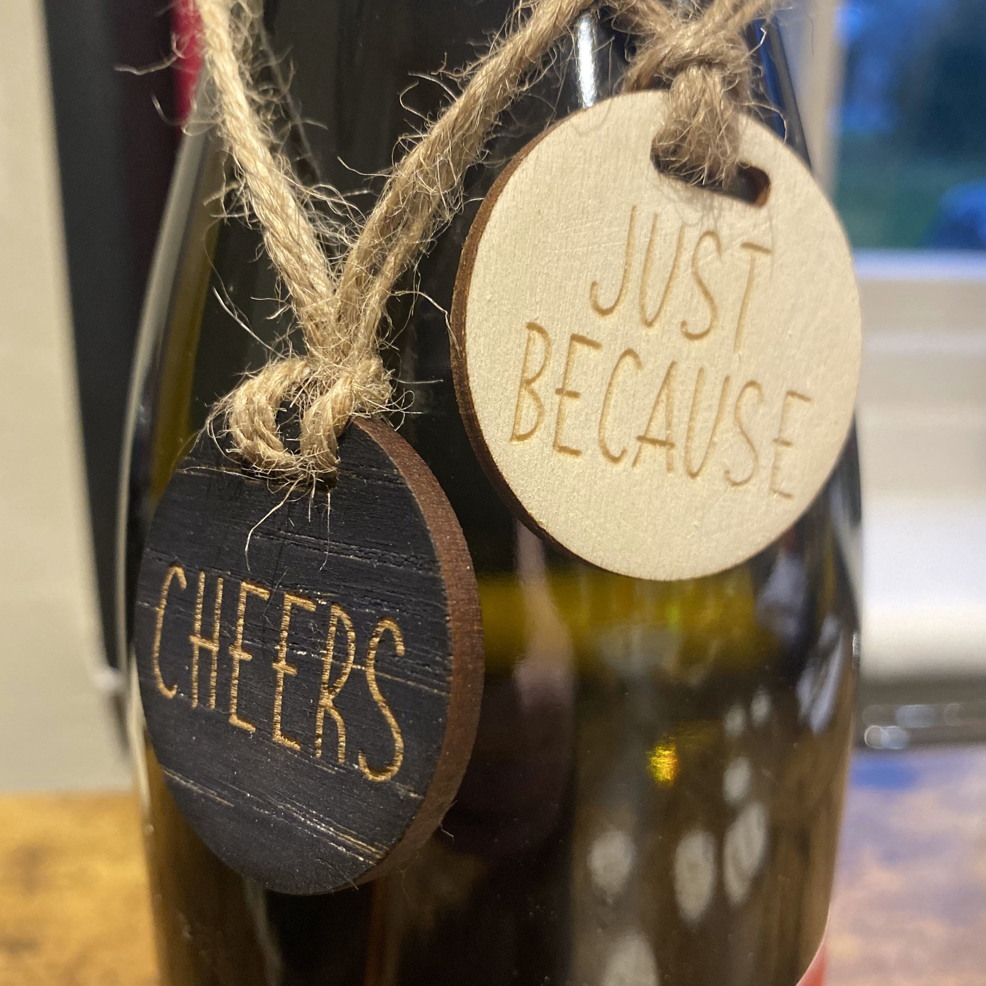 Celebration-themed wooden charms with engraved messages – ‘Cheers’ and ‘Just Because' for wine bottle gifting