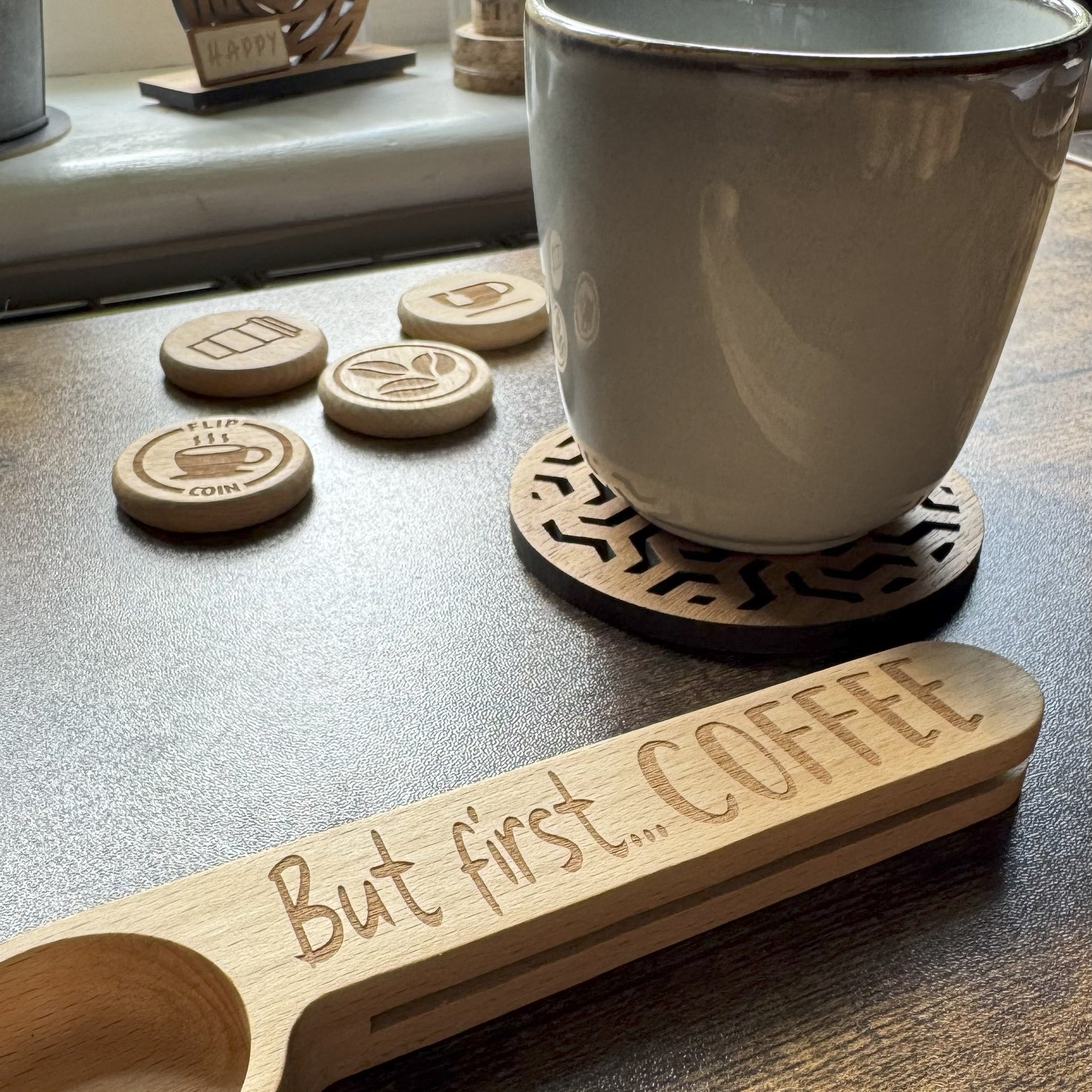 Engraved coffee spoon with mug  of coffee, with coins flipped in the background, styled for a playful and cosy beverage moment