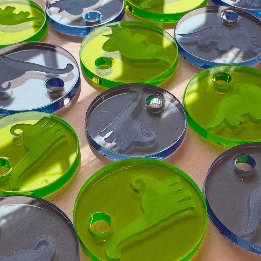 Engraved acrylic tags featuring fun dinosaur designs, ideal for kids’ gifts or party bags