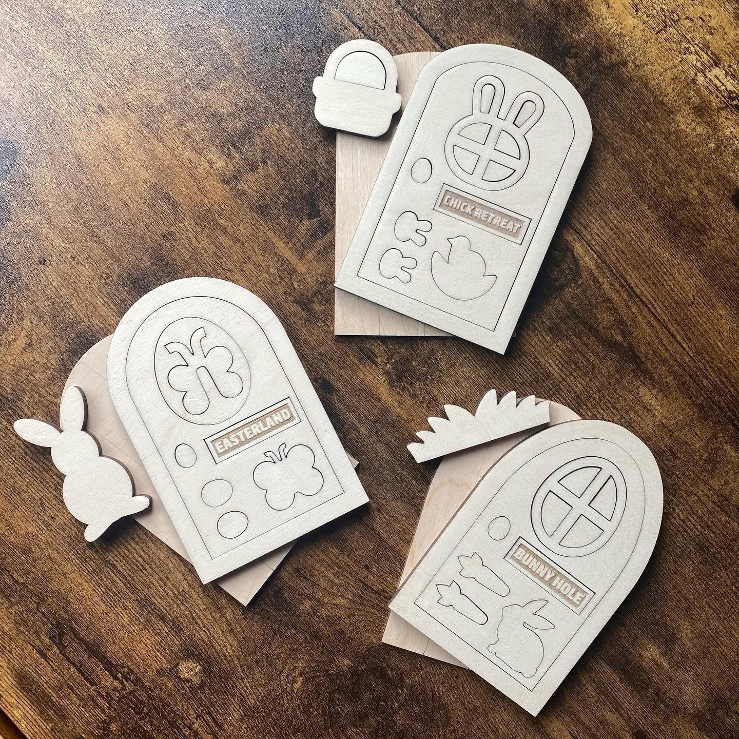 Top-down view of a trio of Easter bunny door kits, featuring intricate cut details and seasonal designs