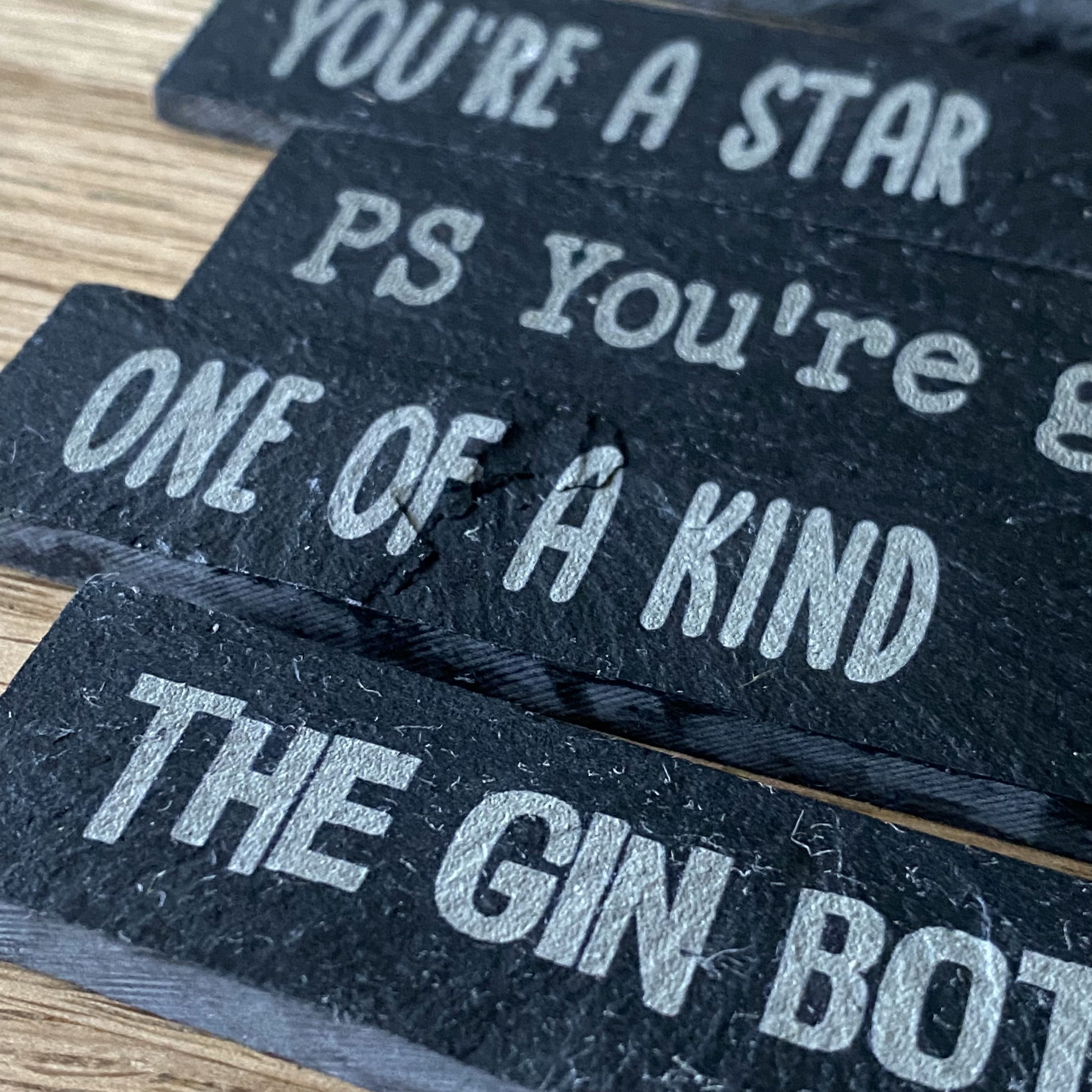 Side-angled detail of engraved slate plant markers with mixed designs