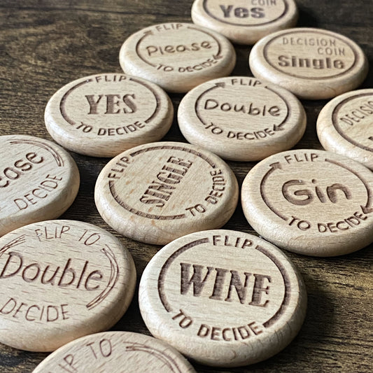 Angled close-up of mixed Friday Night Drinking Trio Flip Coins, highlighting the engraved details and natural wood texture across different designs