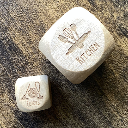 Top-down view of two sizes of engraved wooden Household Chores Decision Dice set side by side, showing detailed task engravings and smooth finish