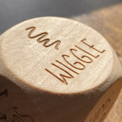 Close-up detail of "wiggle" engraved on a wooden Junior Exercise Decision Dice, with clear playful illustration