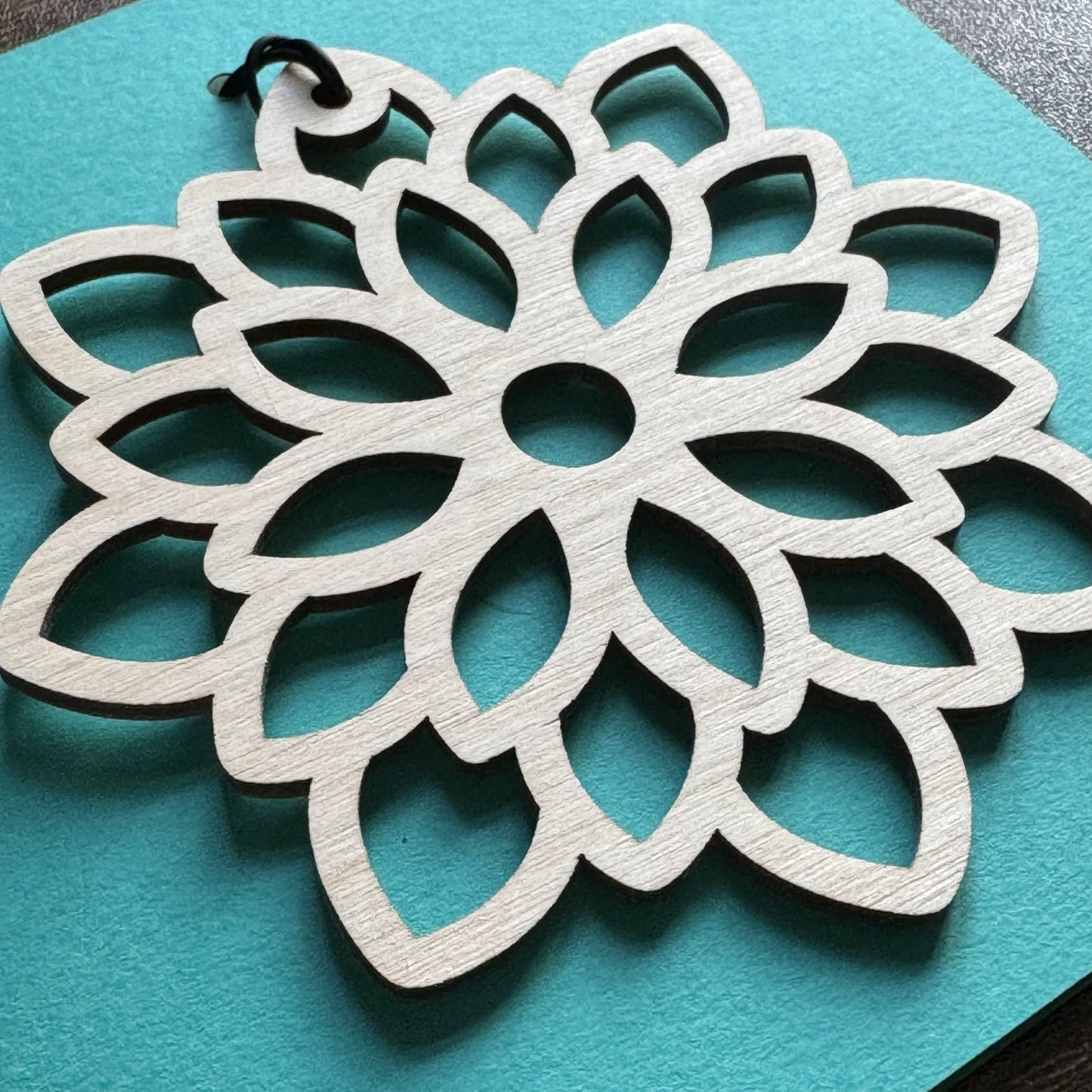Close up view of Keepsake Charm Card displaying an intricate wooden mandala charm with matching ribbon, showing clean laser cut finish