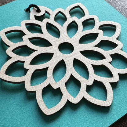 Close up view of Keepsake Charm Card displaying an intricate wooden mandala charm with matching ribbon, showing clean laser cut finish