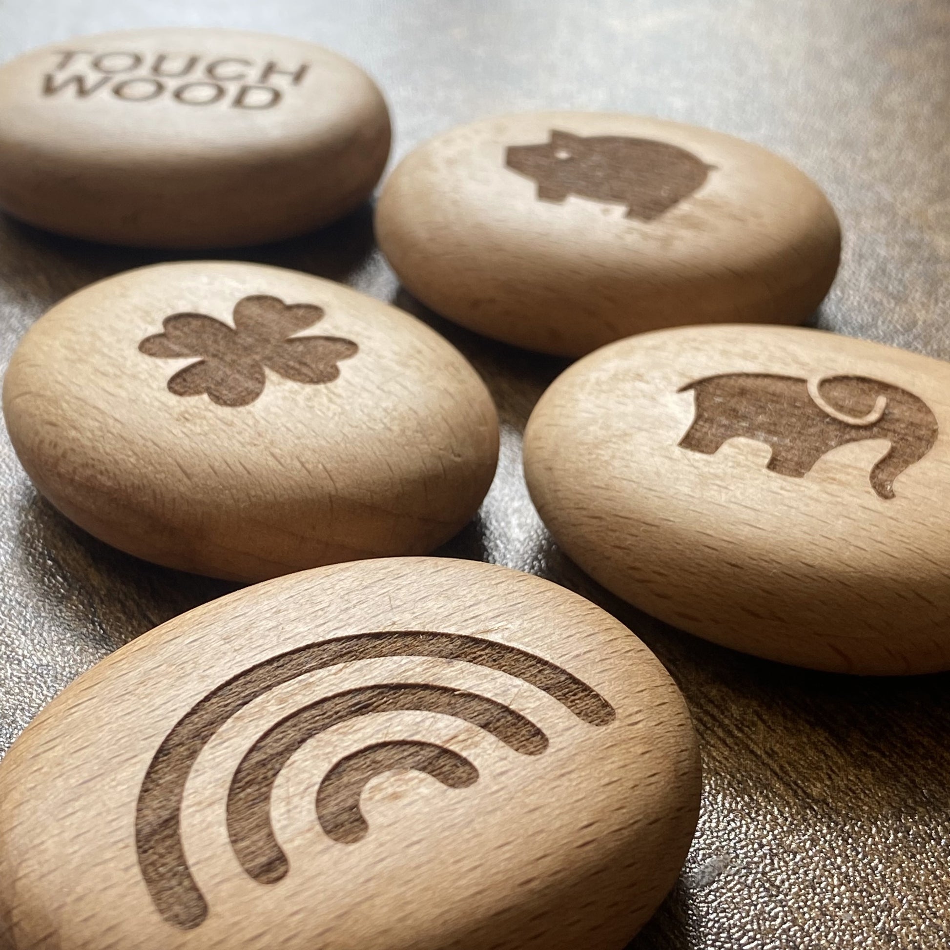 "Angled group shot of Luck Edition pocket pebbles – engraved wooden tokens with symbols of fortune and protection
