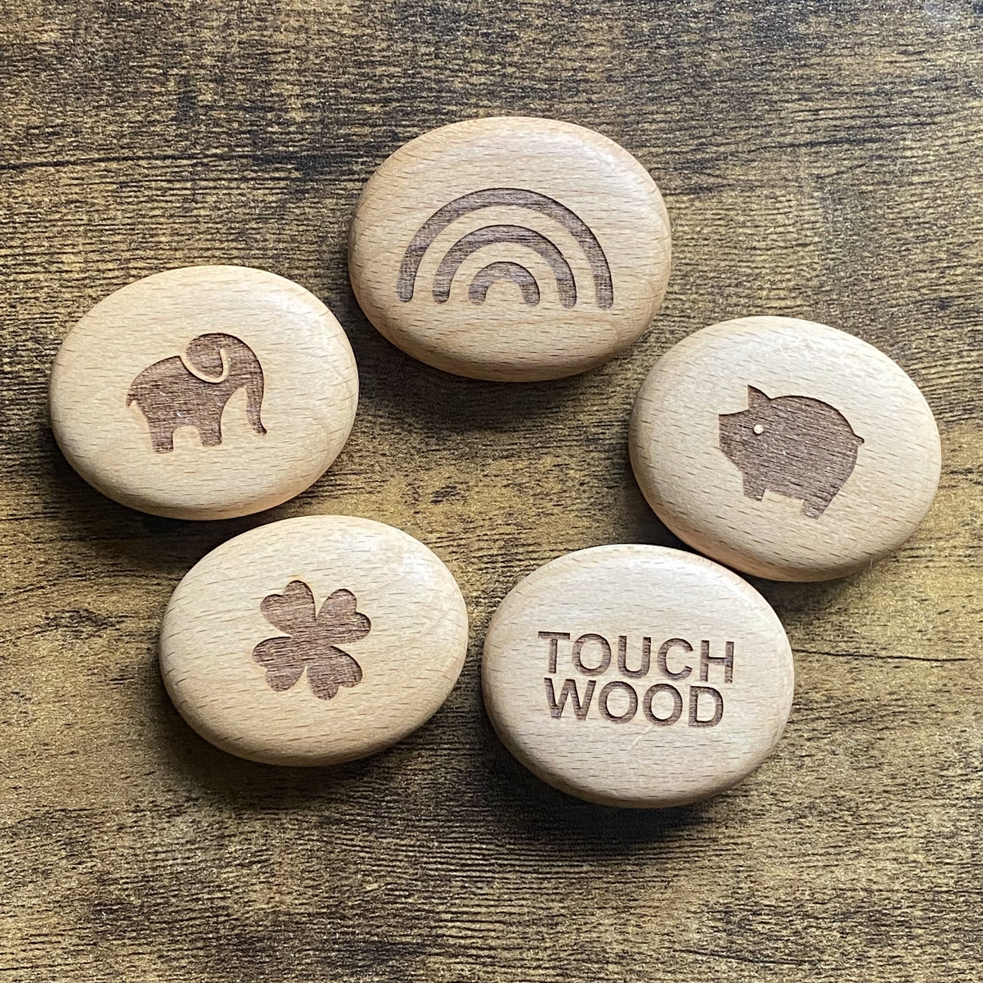 Top-down view of all Luck Edition wooden pocket pebbles – engraved with traditional good luck symbols and arranged as a set