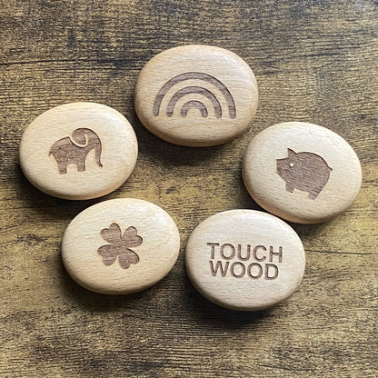 Top-down view of all Luck Edition wooden pocket pebbles – engraved with traditional good luck symbols and arranged as a set