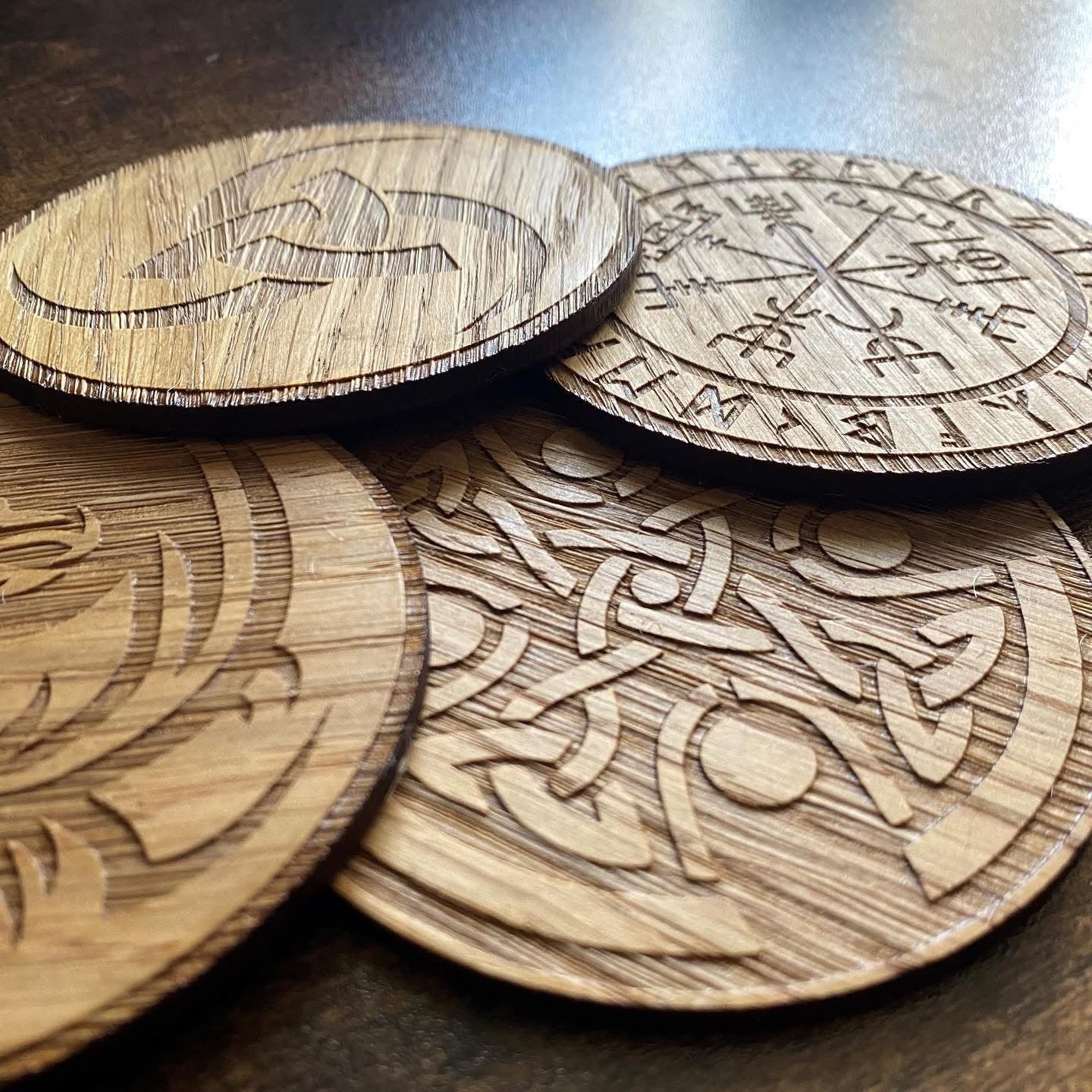 Set of oak coasters engraved with Norse-inspired designs, featuring intricate symbols and natural wood grain