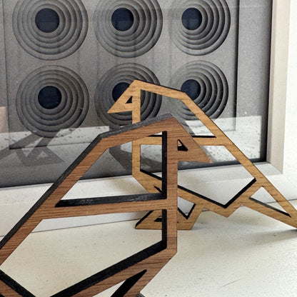 Wooden bird ornaments in front of geometric papercut artwork – origami-inspired modern wall display