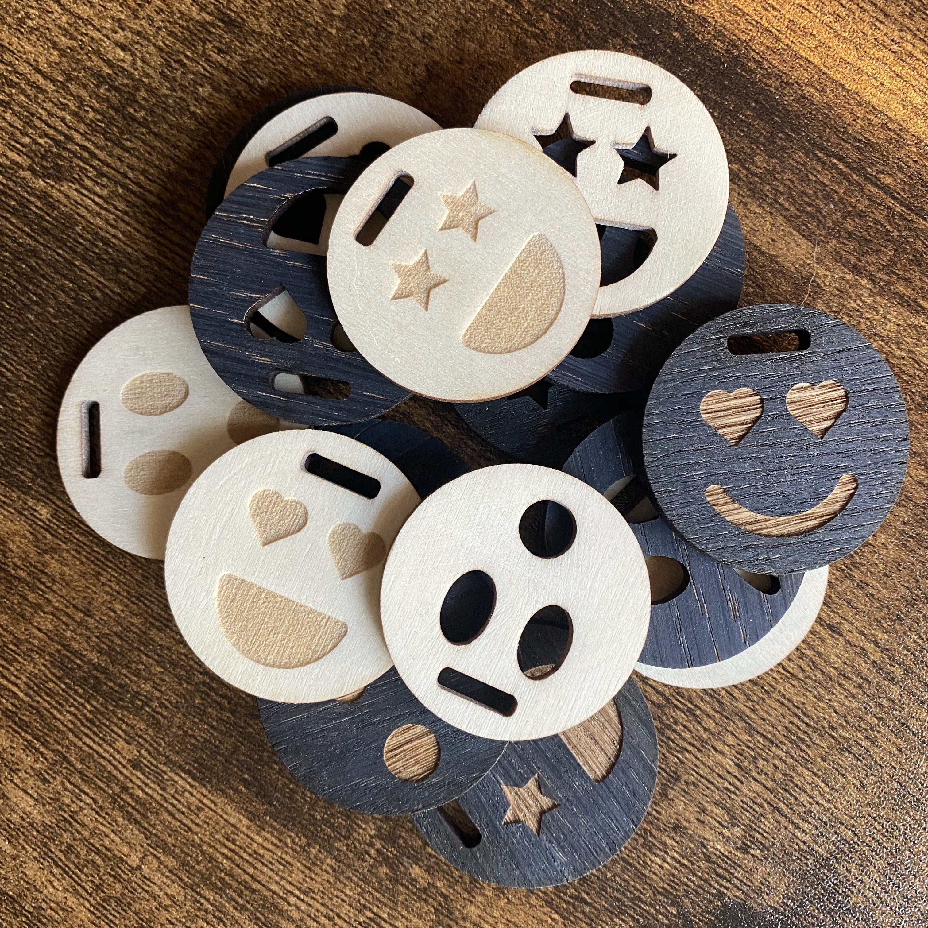 Stack of engraved wooden emoji tags with expressive character faces